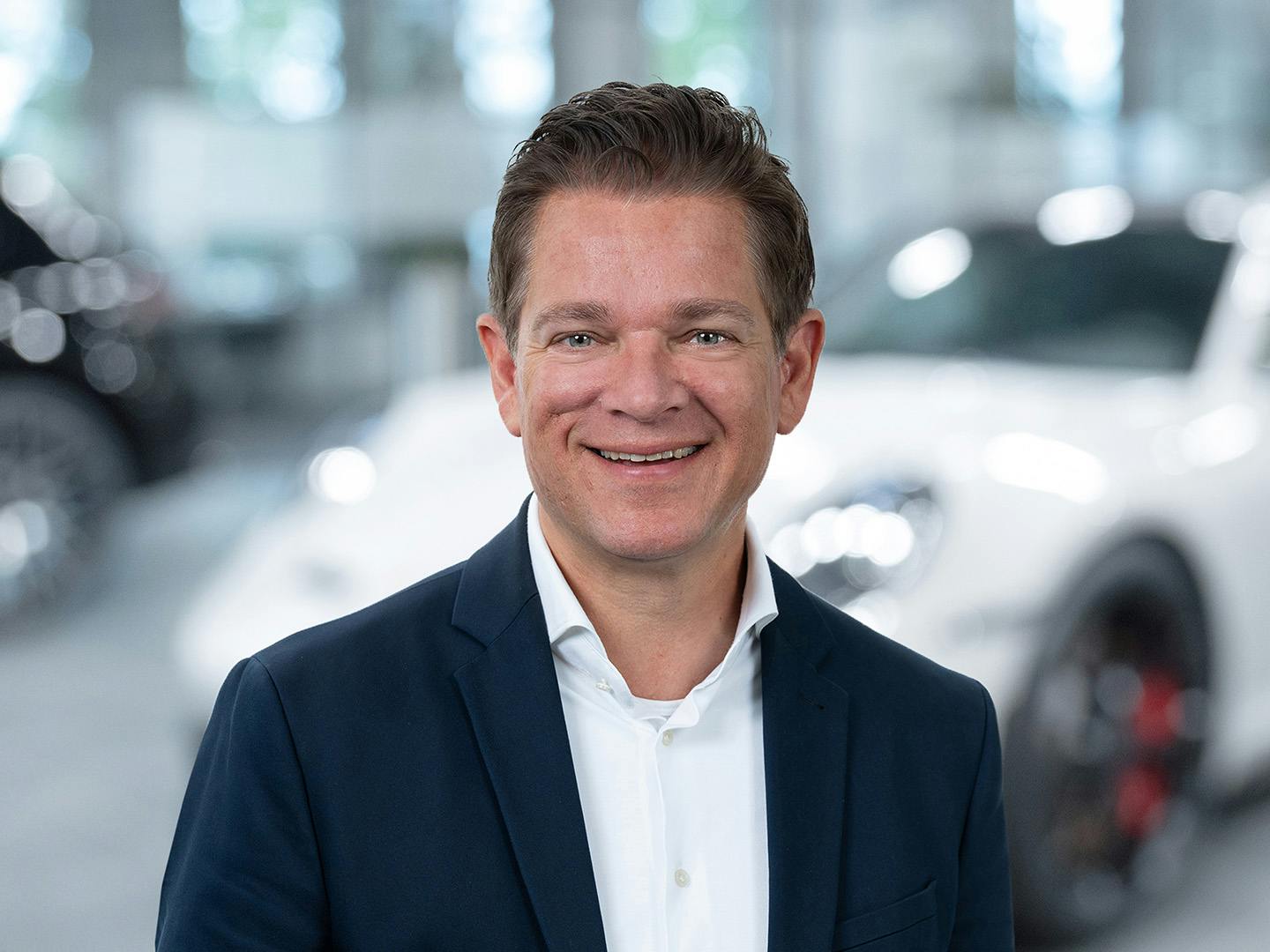 Porsche Mitarbeiterin berät einen Kunden der in einem Porsche Fahrzeug sitzt.
