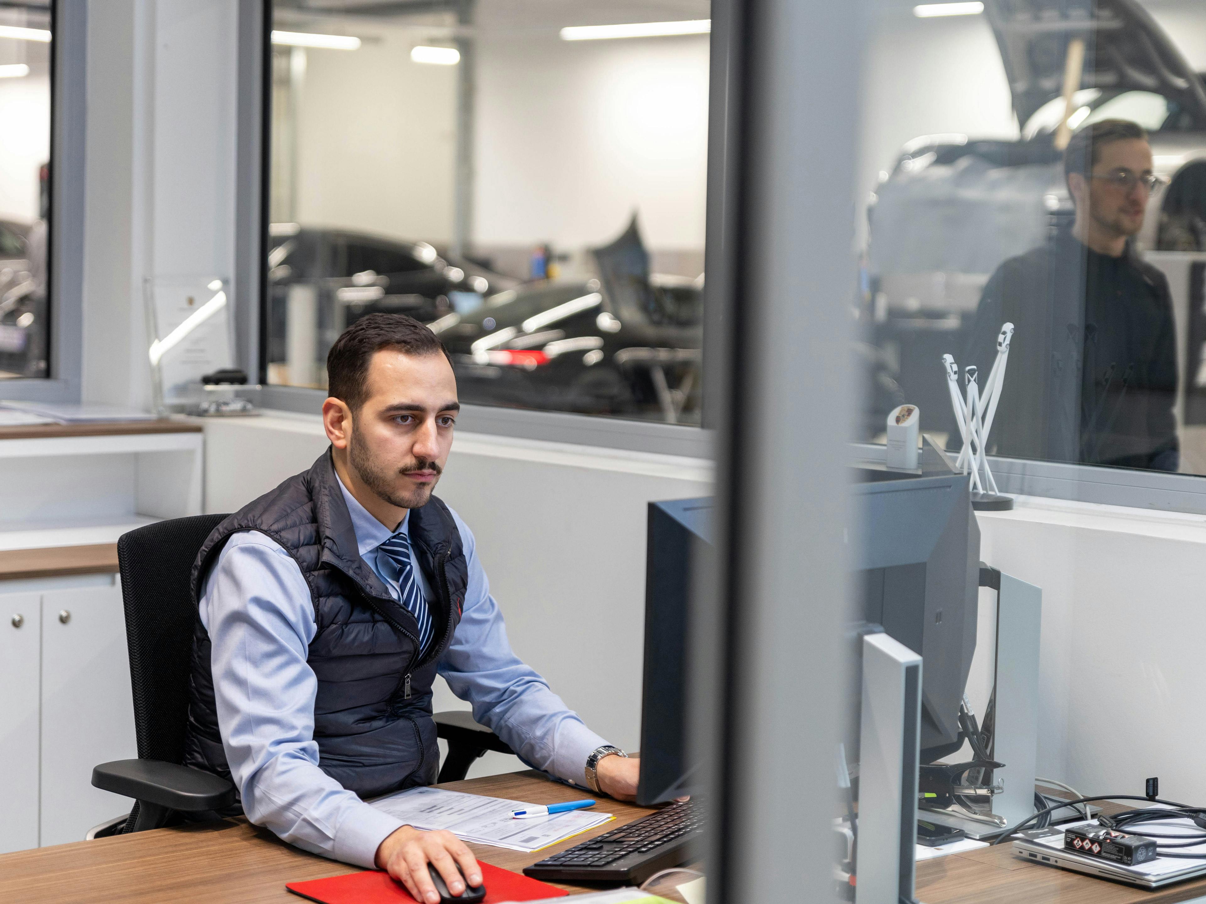 Un collaborateur de Porsche, assis derrière un bureau et travaillant sur un ordinateur devant lui.