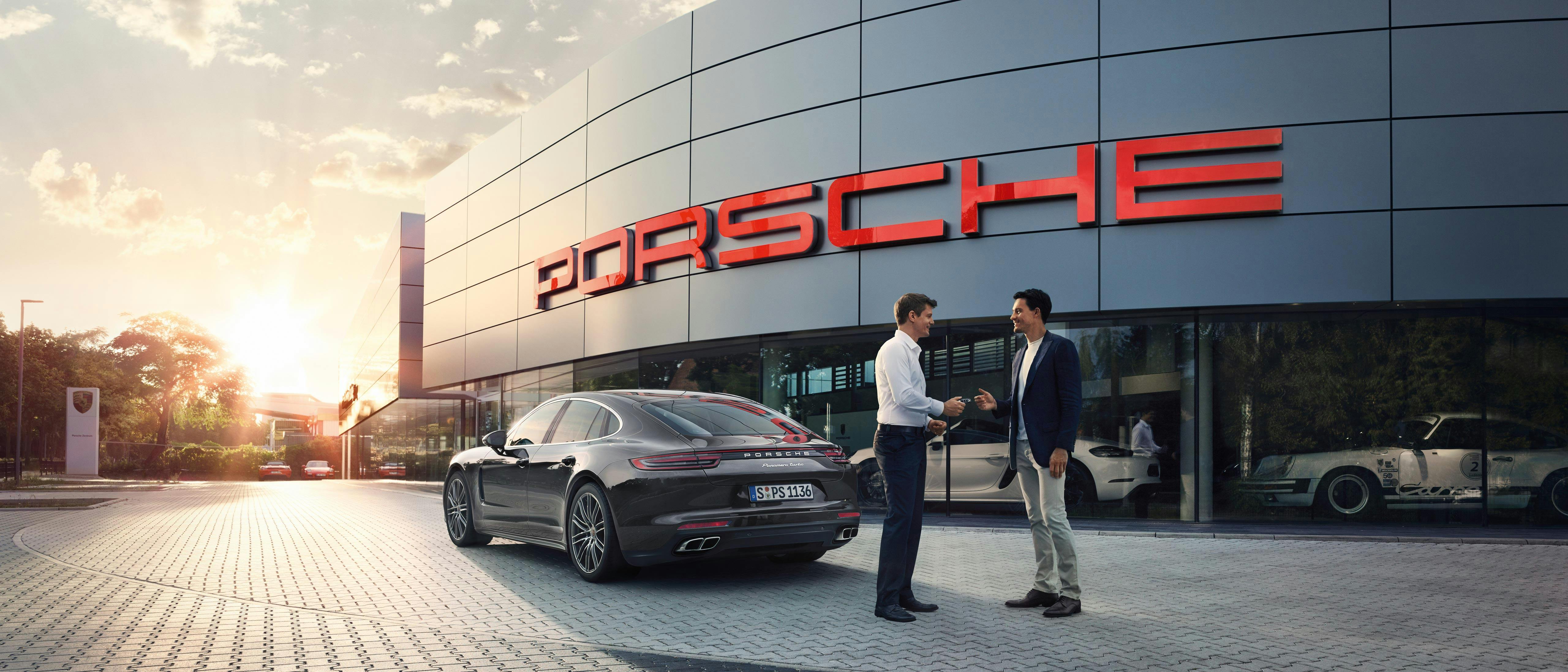 Schlüsseübergabe vor einer Porsche Niederlassung
