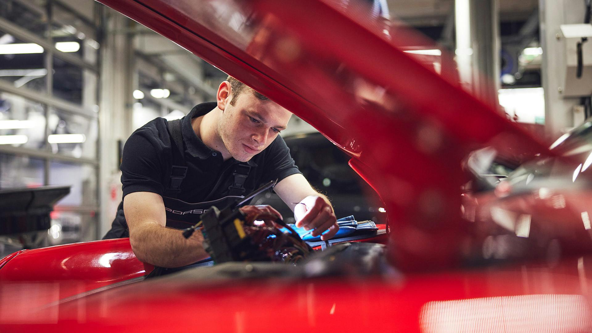 Porsche technician working on red classic Porsche vehicle
