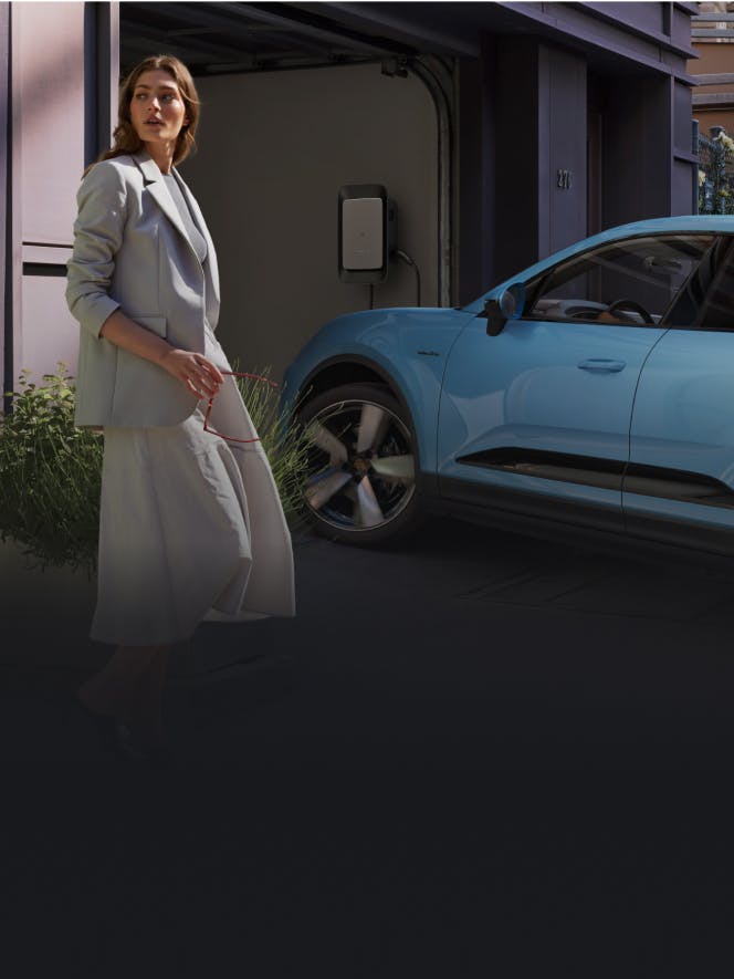 Porsche Macan drives into a garage. A woman stands in the foreground.