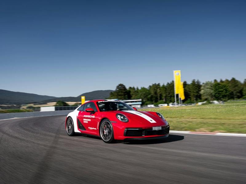 Ein roter Porsche 911 fährt auf der Rennbahn des Porsche Driving Center Lignières.
