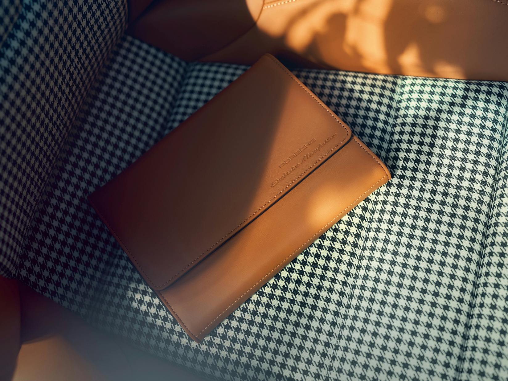 View of the seat of the Porsche 911 Sport Classic with seat centre in Pepita pattern. A leather vehicle folder is lying on it.