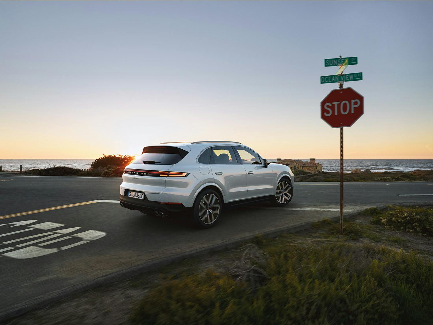 Un Porsche Cayenne Coupé, arrêté à un stop, en face de l'océan.
