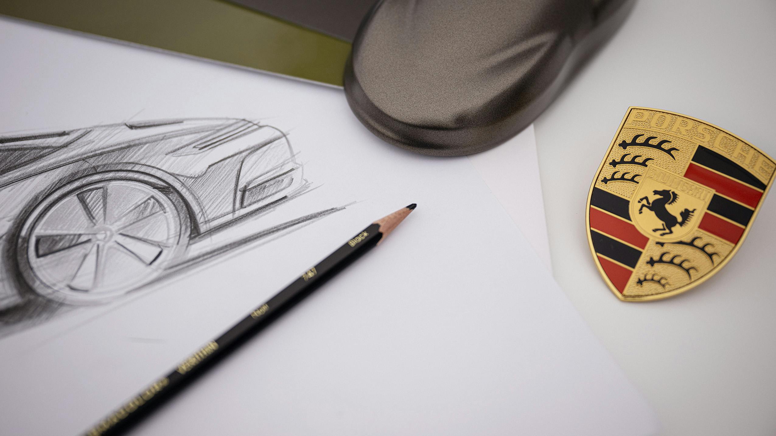 Design sketch of the Porsche 911 Spirit 70 with pencil, paint frog and Porsche crest on white paper.