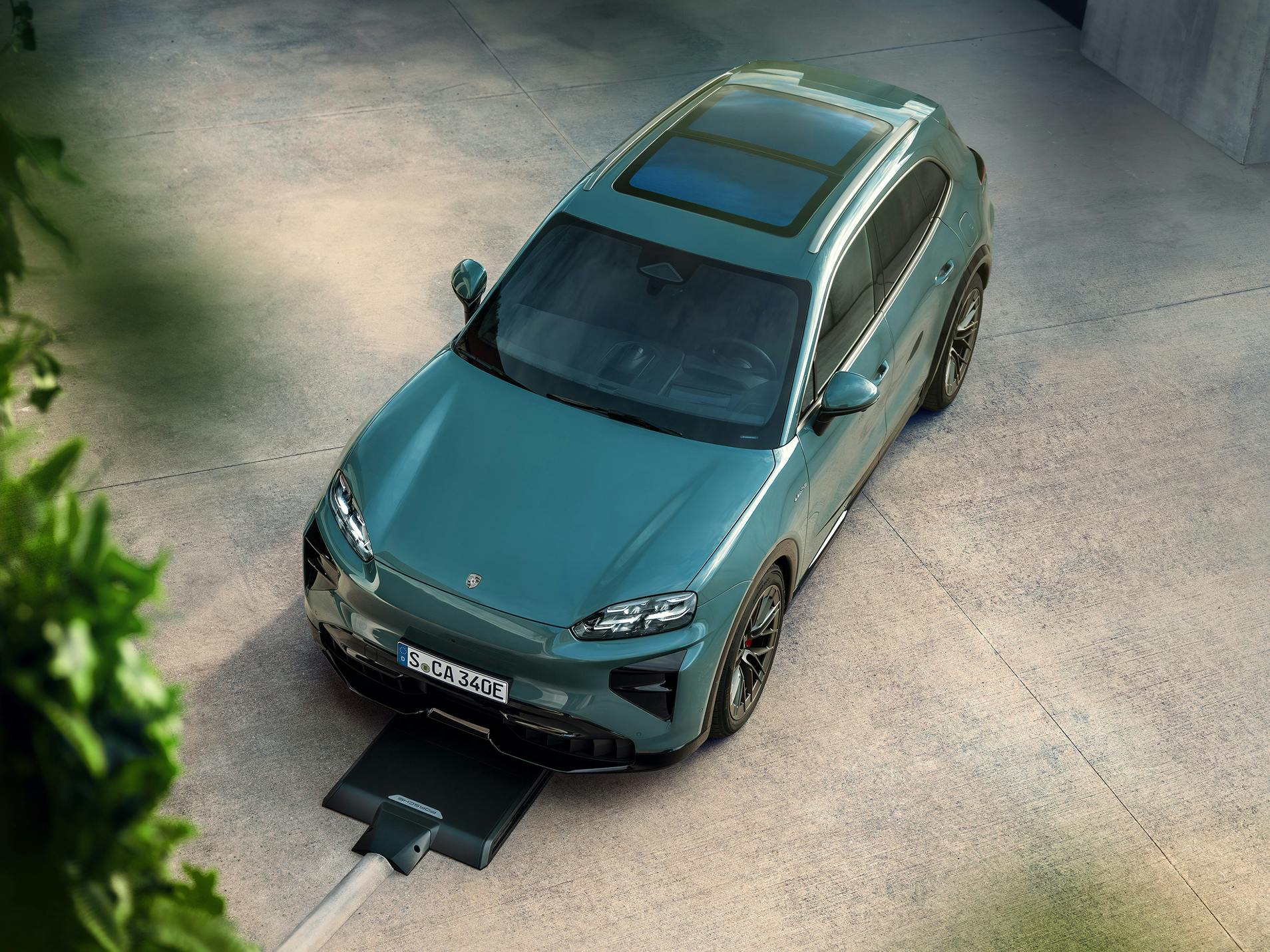A Porsche Cayenne Electric stands in front of a charging plate of the Porsche Wireless Charging System.