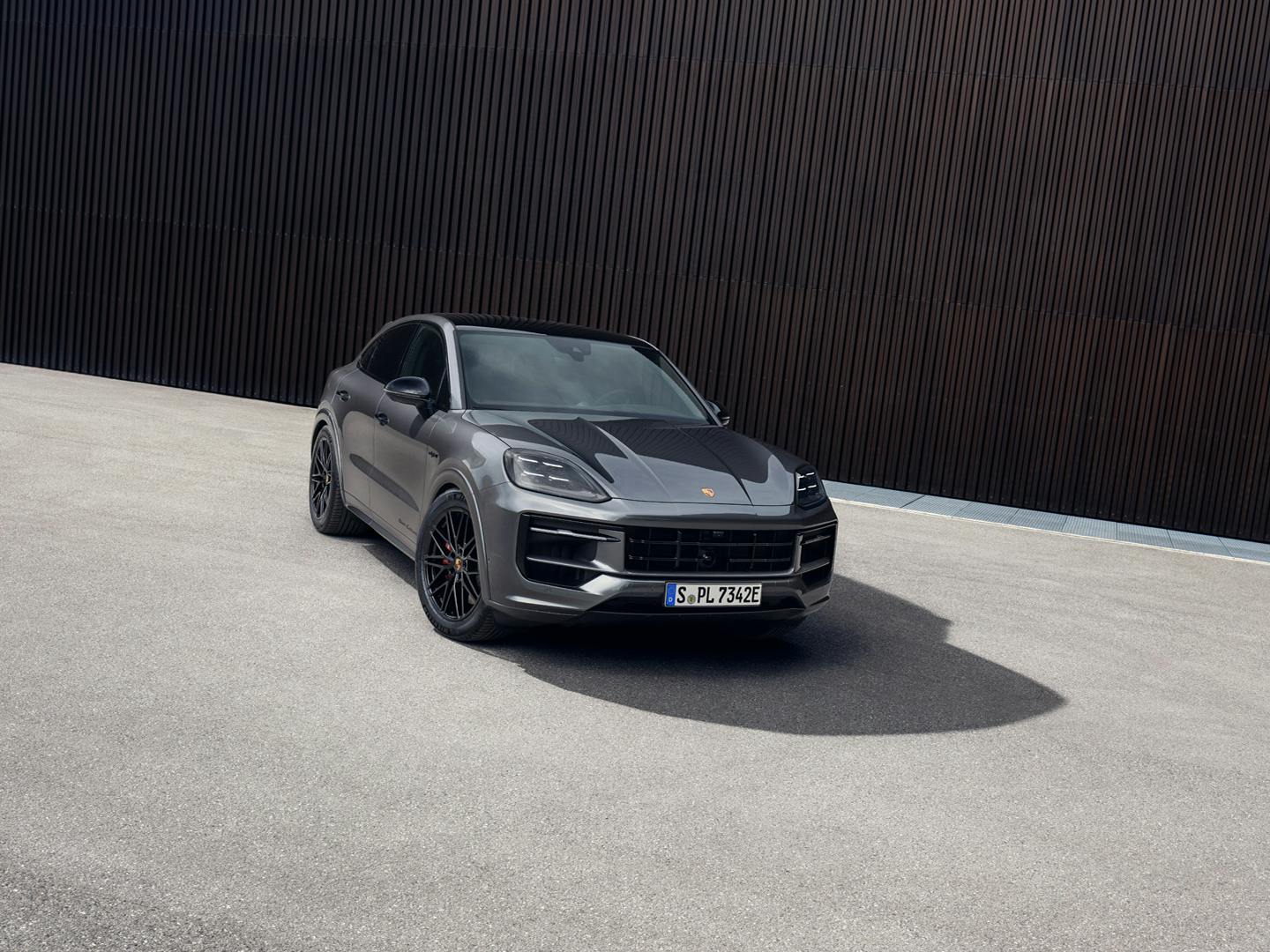 The Cayenne S E-Hybrid Coupé Black Edition parked outside a tall brown building.