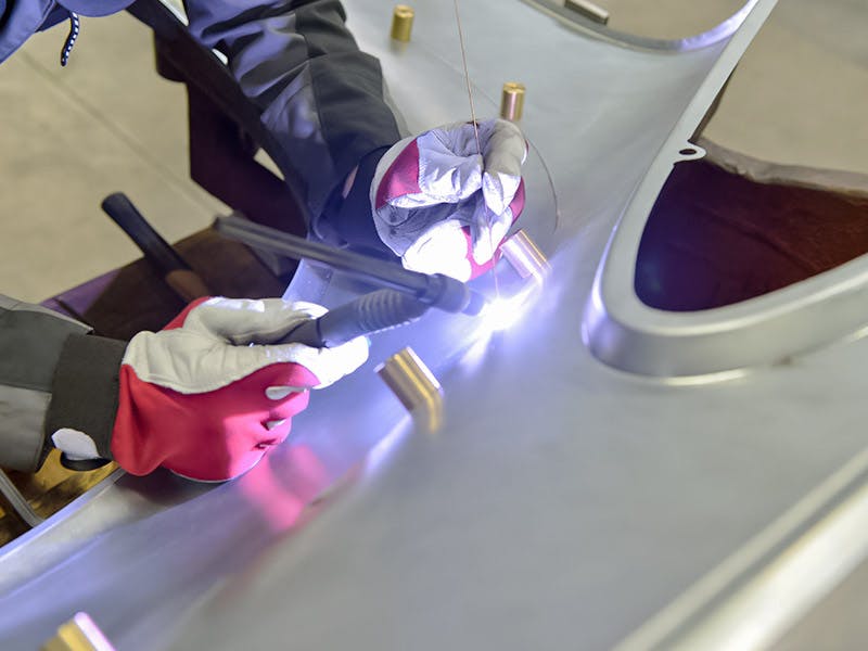 Detail shot: wing, gloved hands with light tool.