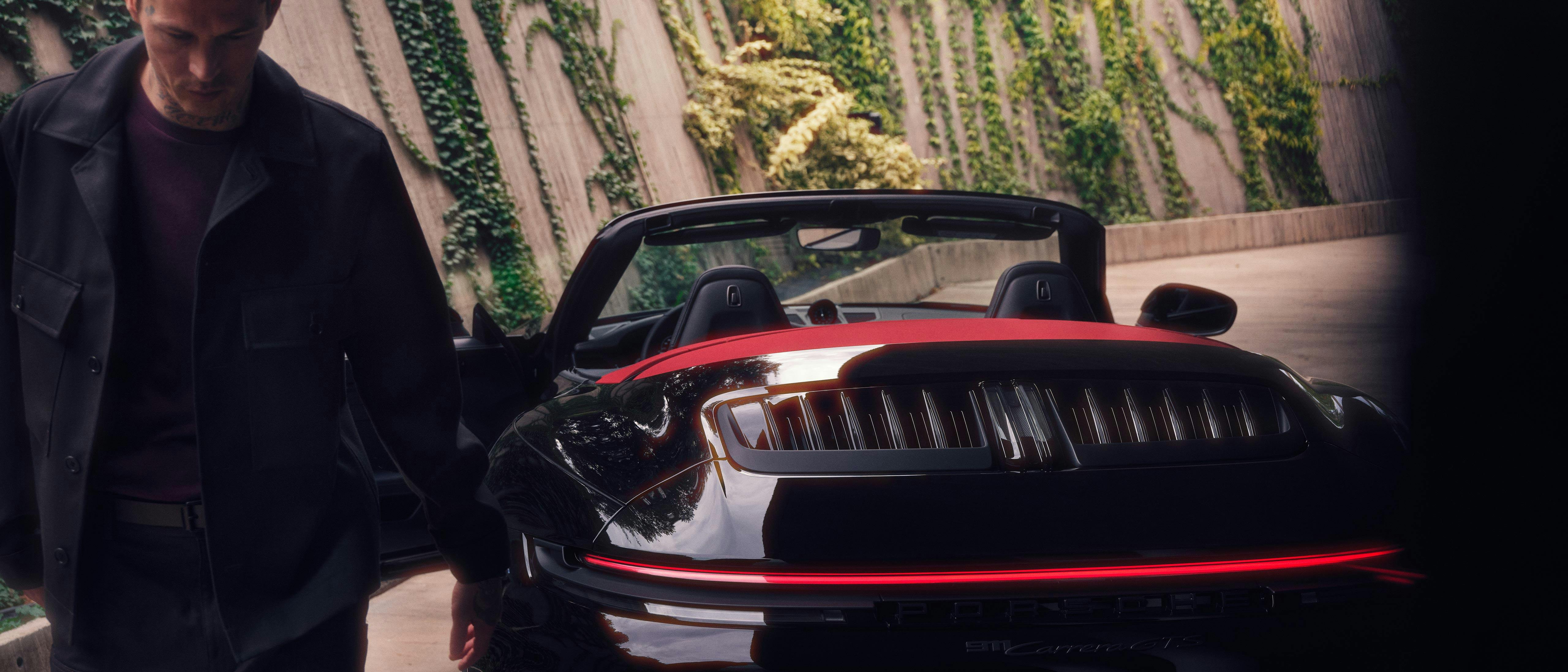 Un homme marche à côté d'une Porsche GTS Cabriolet.