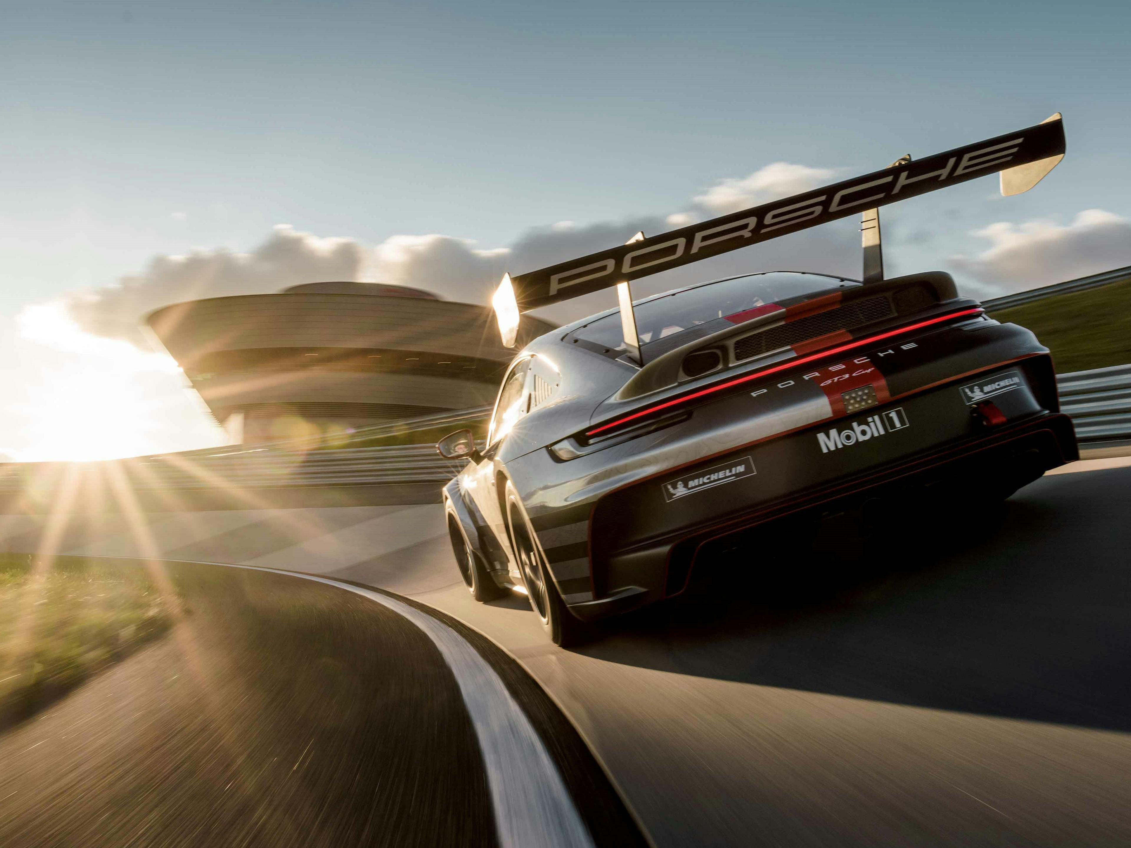 Un coche de carreras Porsche toma una curva a la izquierda en el Porsche Experience Center de Leipzig.