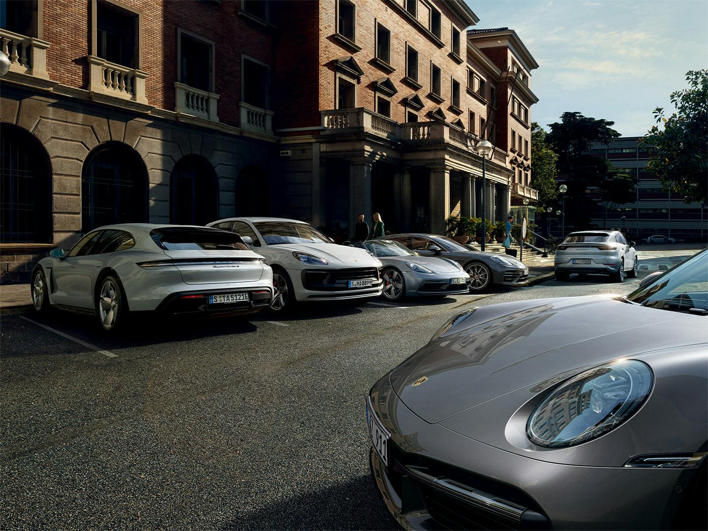 Various Porsche models parked on the side of a street.