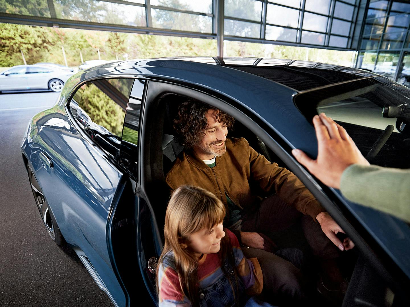 A customer with his daughter inside a blue Taycan