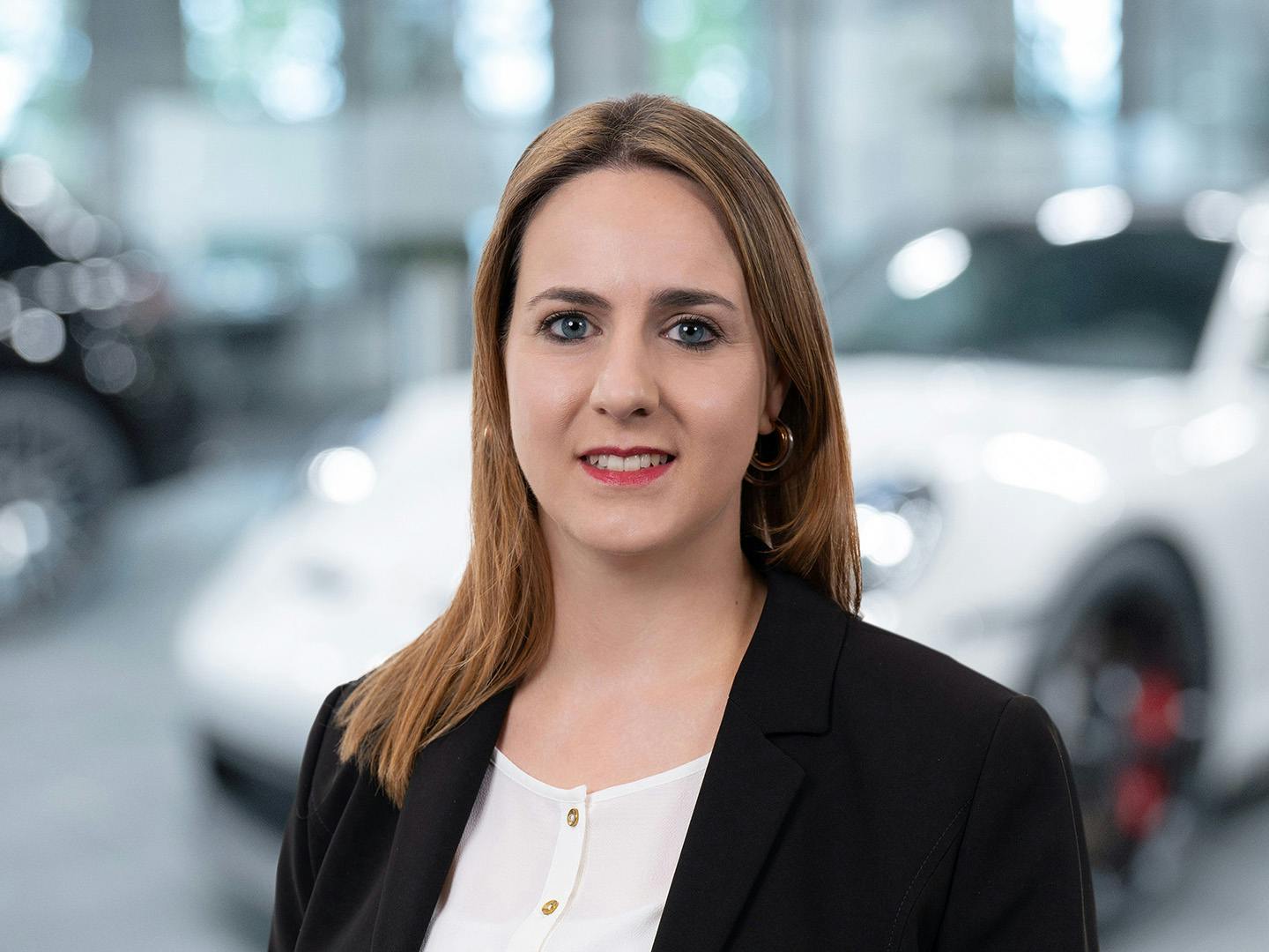 Porsche Mitarbeiterin berät einen Kunden der in einem Porsche Fahrzeug sitzt.