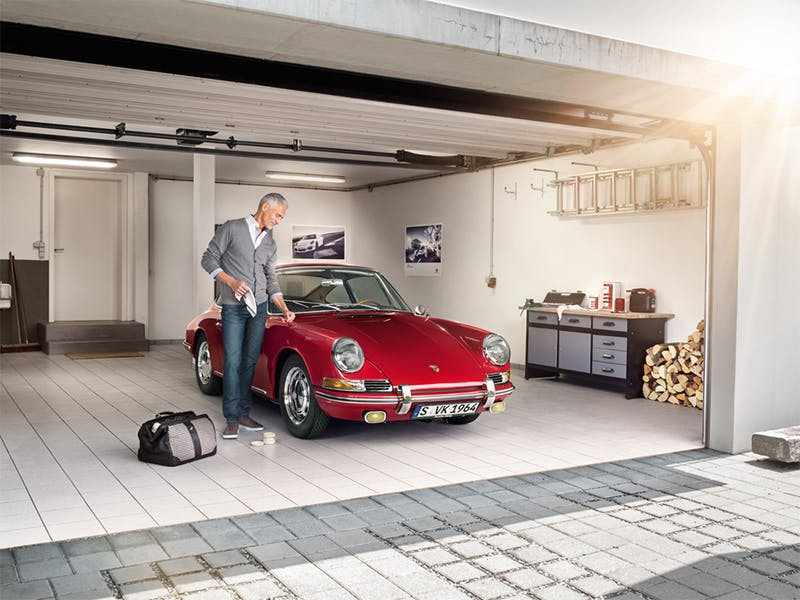 Garage view: Porsche Classic, man cleans a Red Porsche vintage car with a cloth.