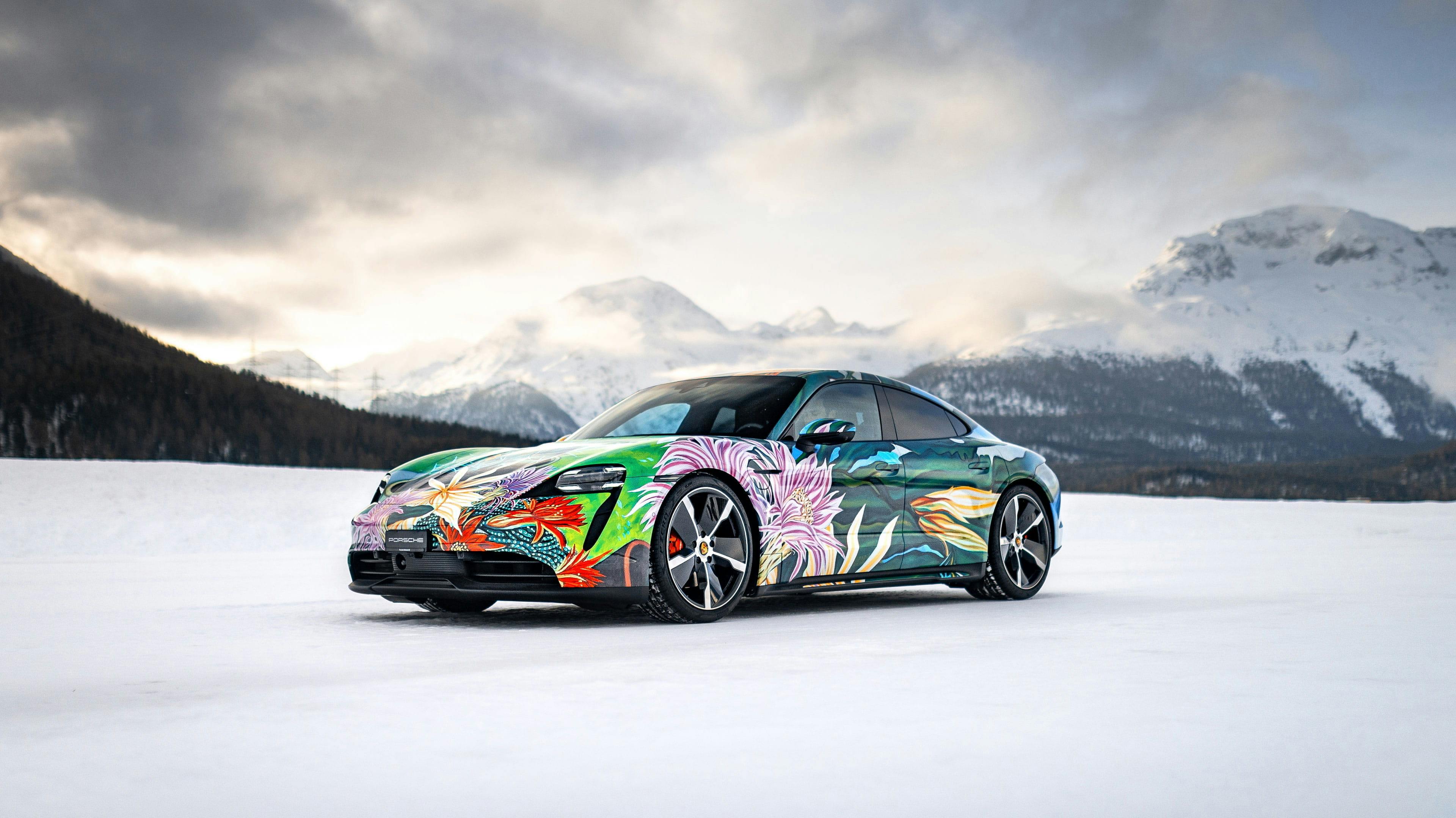 A colourful Porsche Taycan is standing in a snowy field, its painted with flowers, symbolising diversity.
