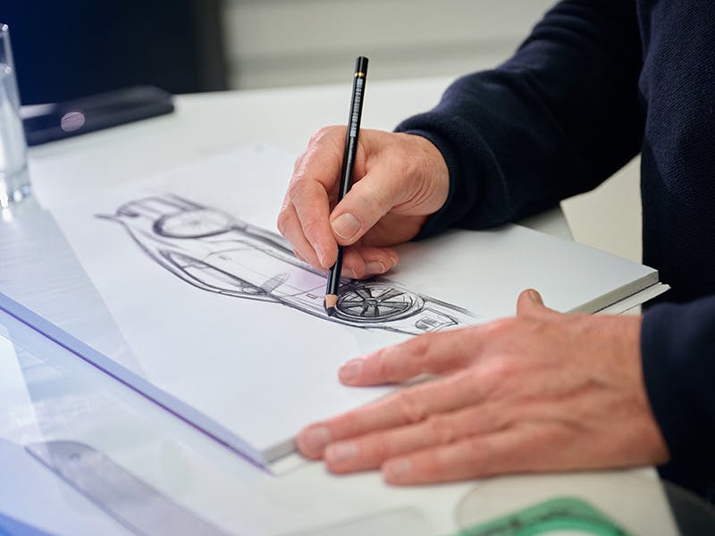 Designer hands with pencil: drawing pad with Porsche model