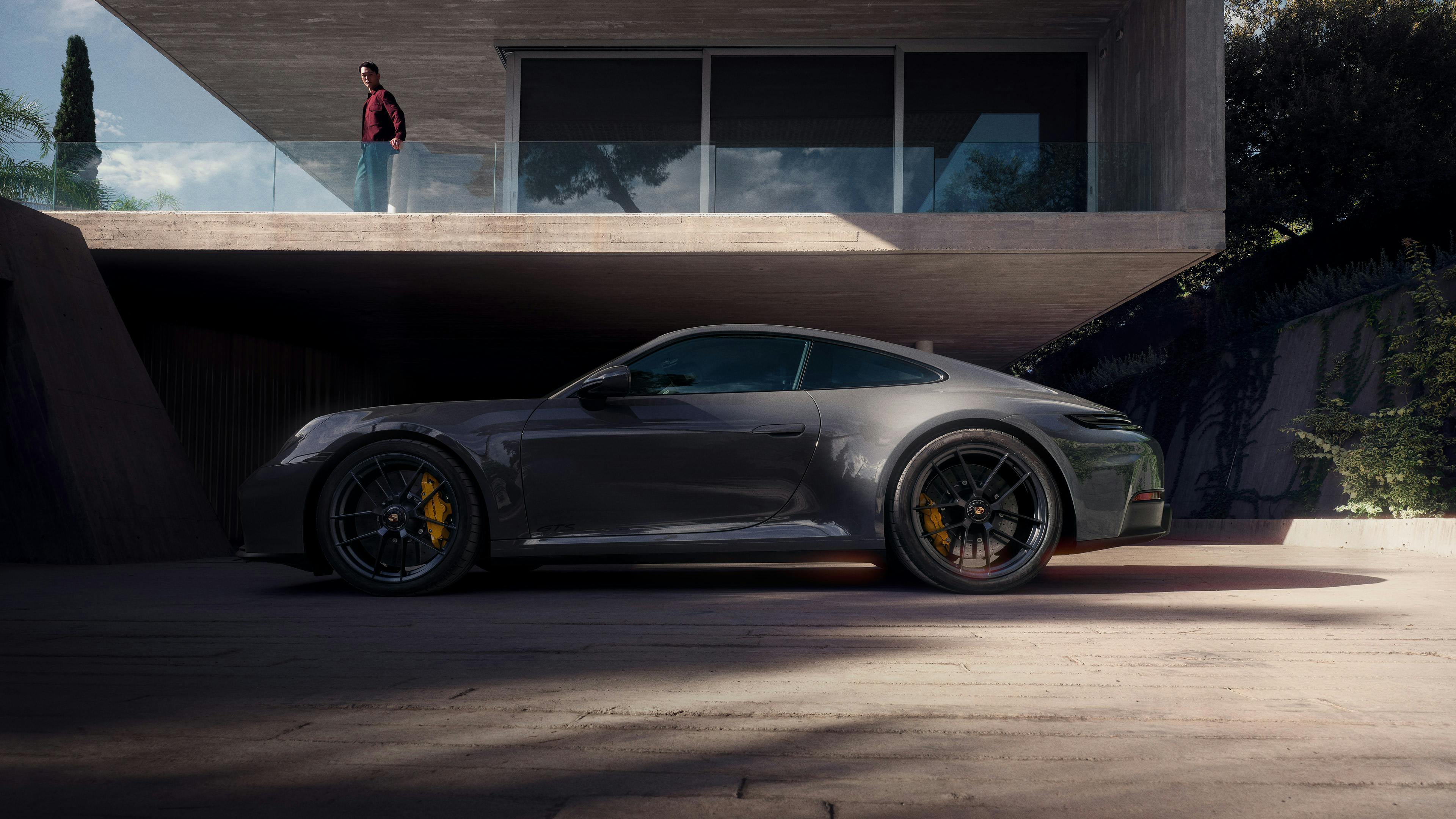 Una Porsche 911 argentata percorre una strada.