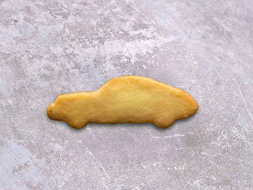 Porsche 911-shaped butter cookie on a textured stone surface.
