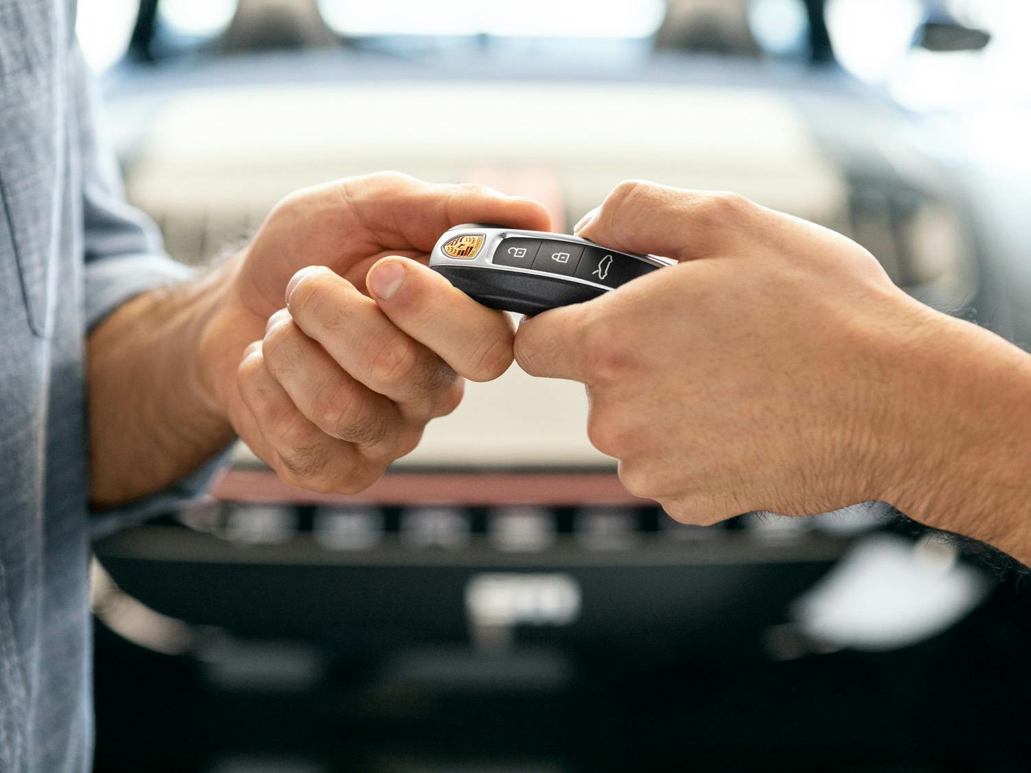 A man handing a Porsche key fob to another person. ​