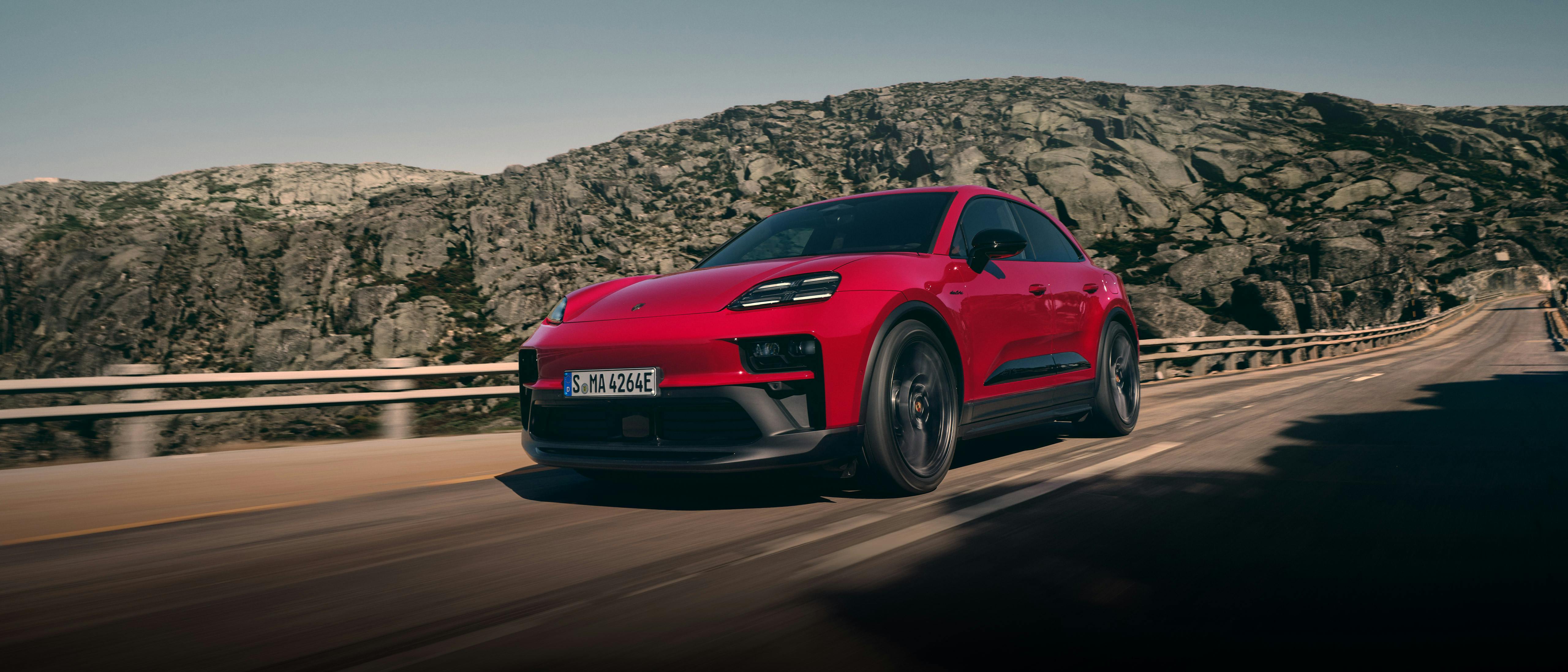 The Macan GTS Electric driving along a road in a mountainous region.