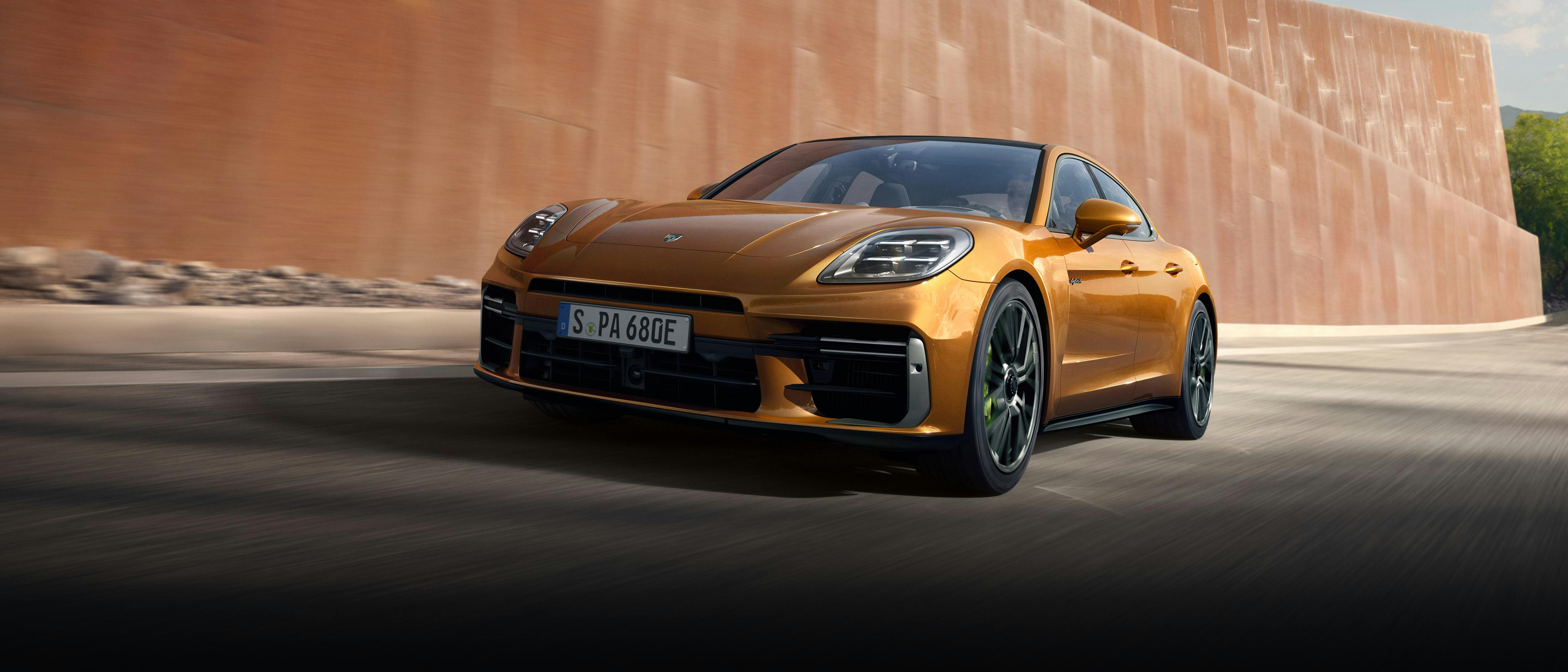 Una Porsche Cayenne blu è parcheggiata sul lato piovoso della strada. Una donna con l'ombrello attraversa la strada.