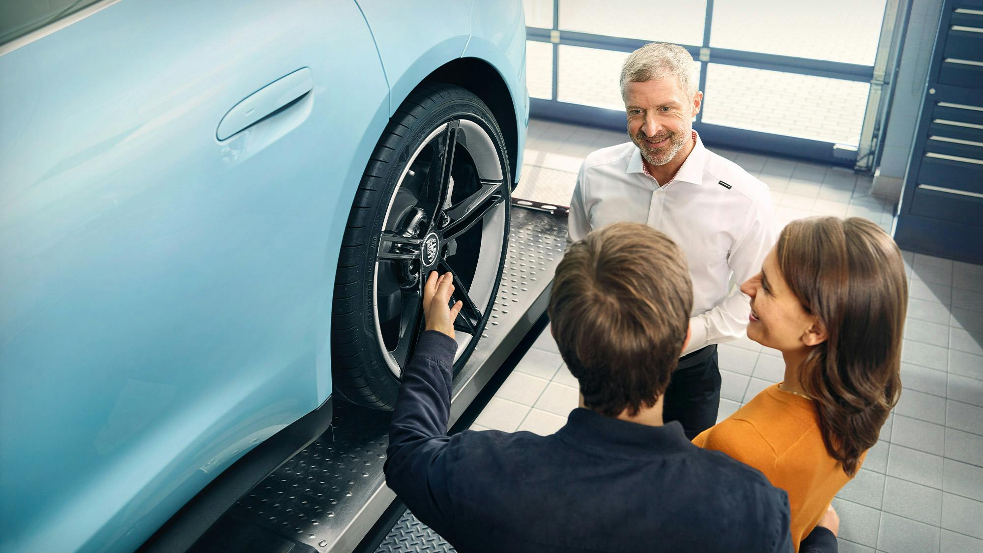 Un manager in giacca e cravatta e un addetto alla produzione con la divisa Porsche, insieme davanti a una vettura non finita, osservano un dettaglio del posteriore della vettura.