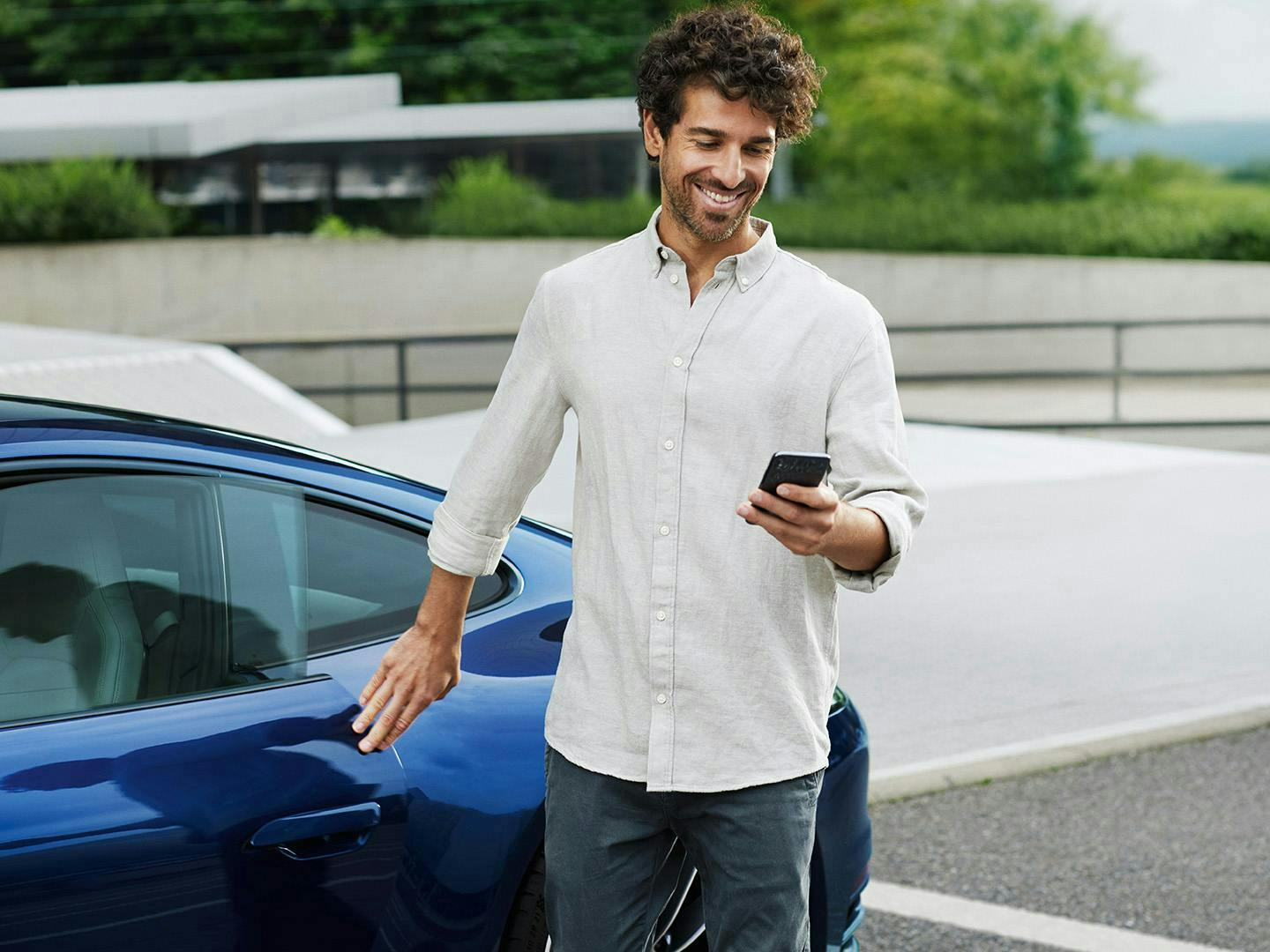 Man smiling while using his smartphone next to a 911 Carrera 4S