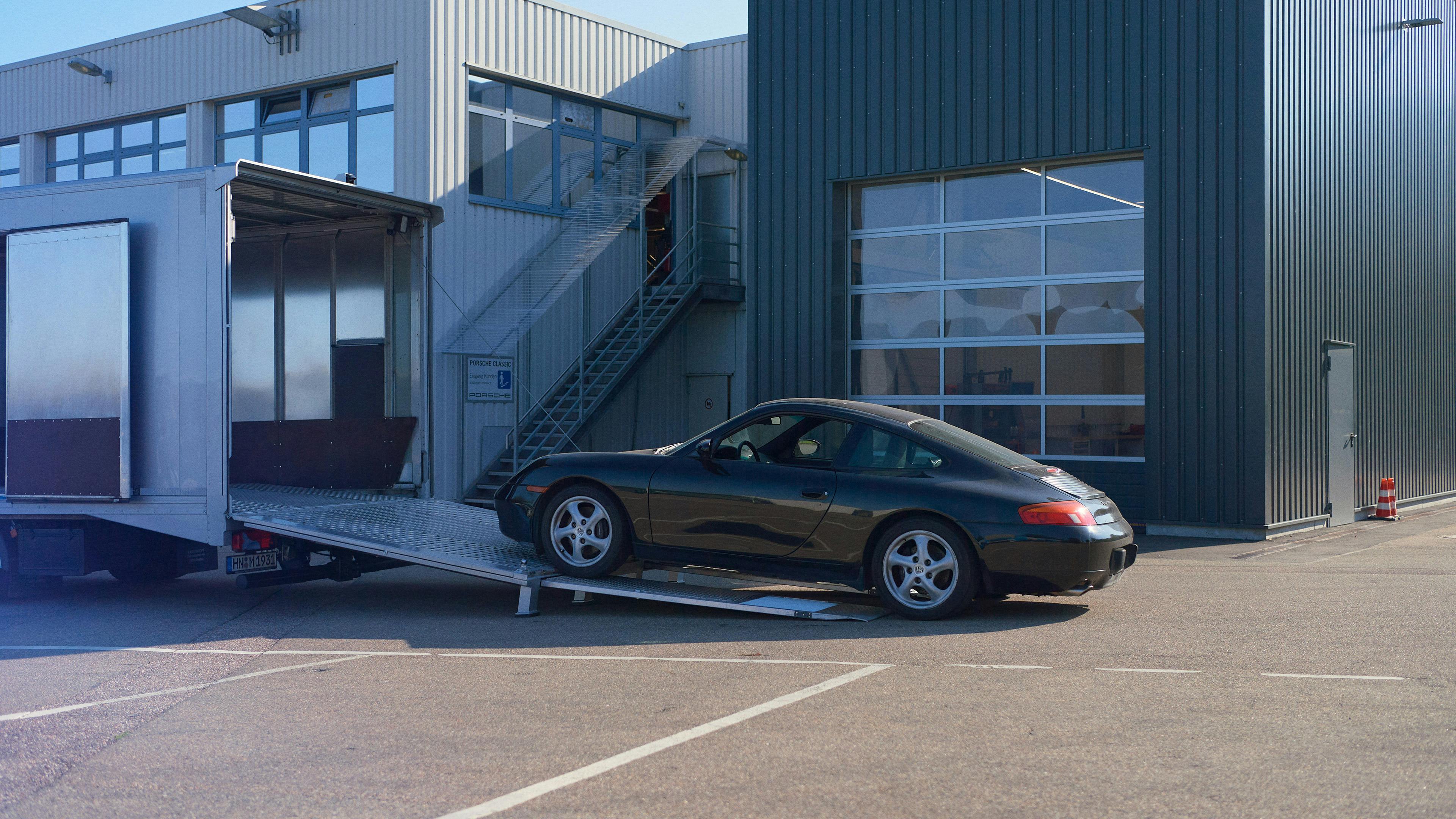 A Porsche 911 Carrera (Type 996) drives up a ramp into a lorry.