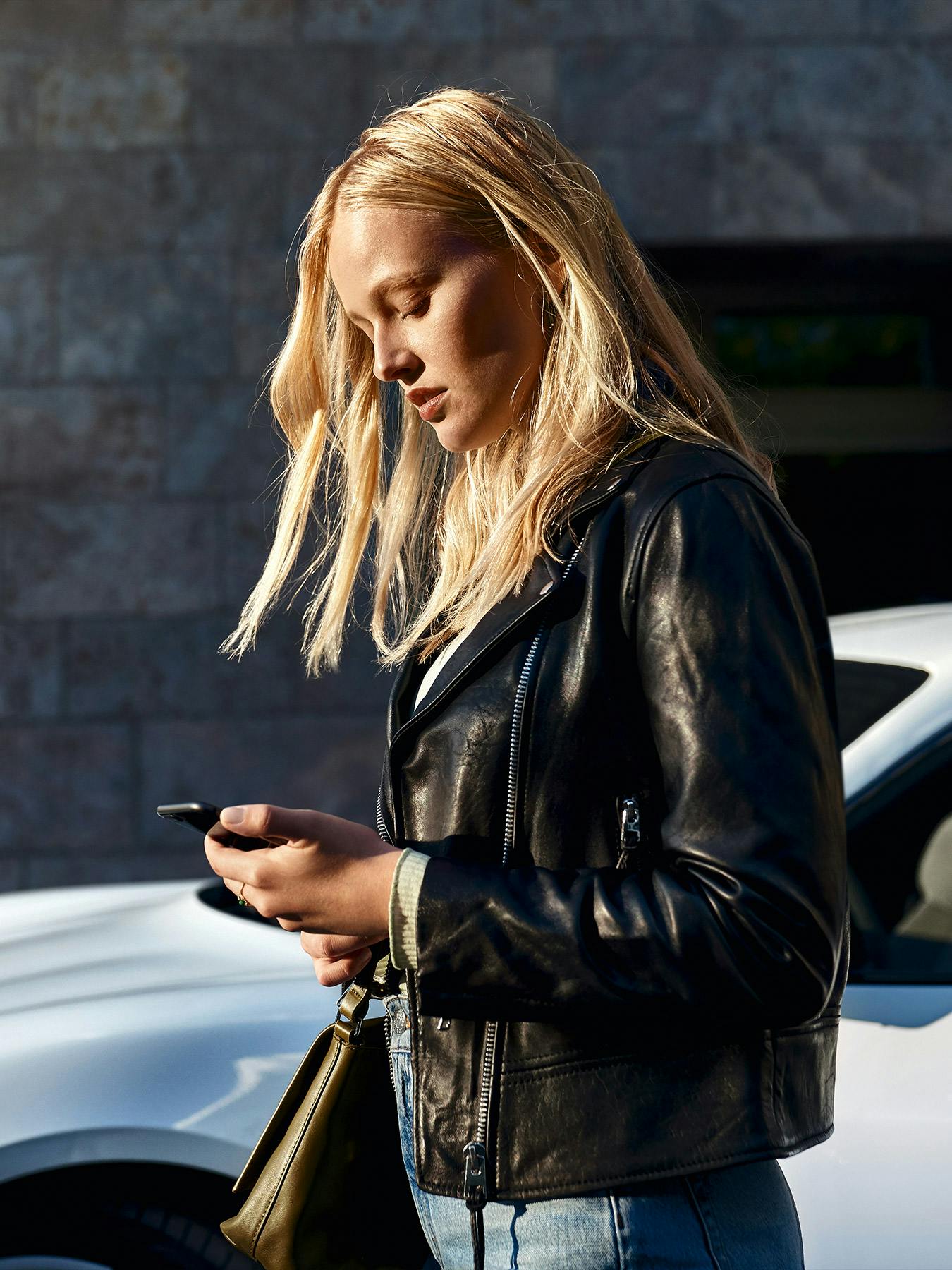 A lady using her mobile phone to interact with her Porsche.