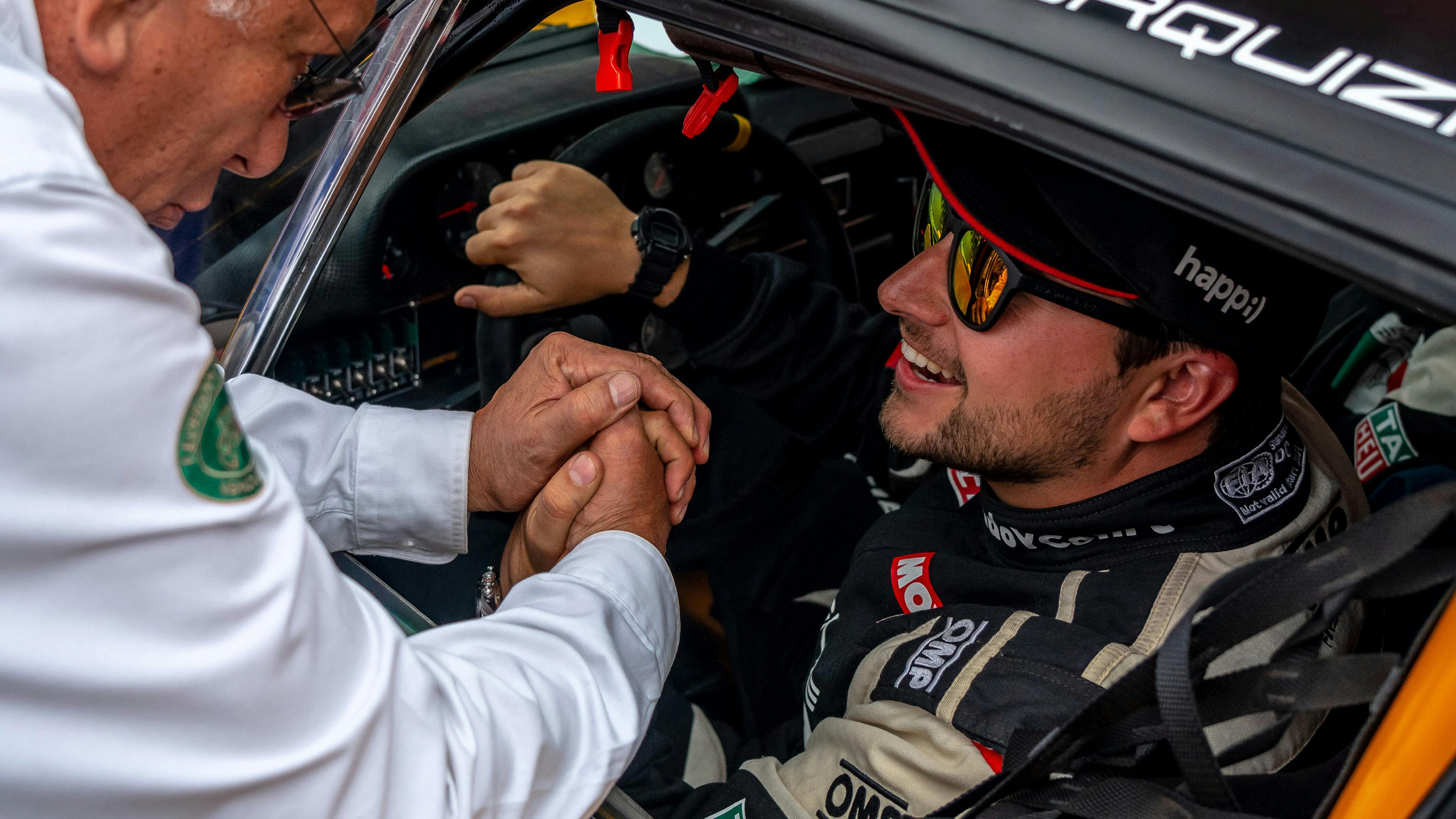 Porsche driver "Fercho" Urquiza greets a fan from the window of his vehicle.