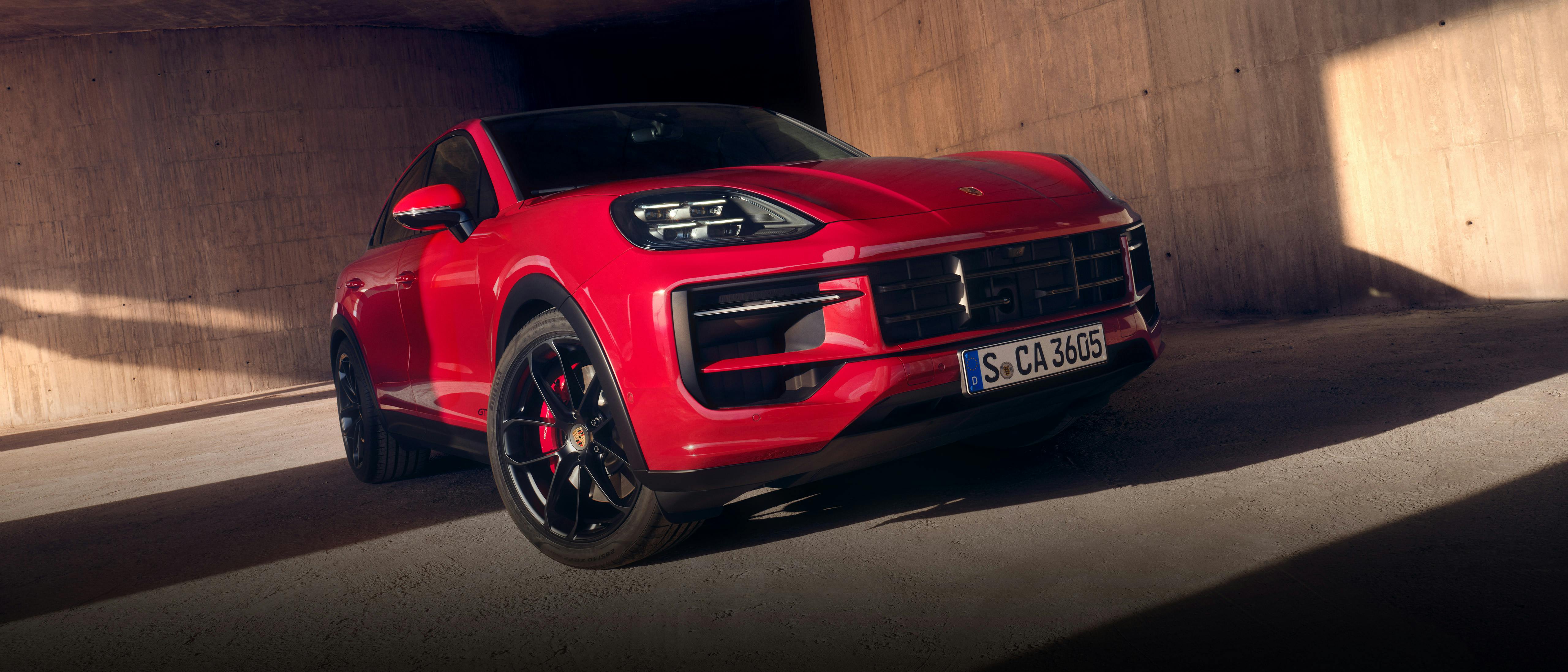 Una Porsche Cayenne blu attraversa una strada cittadina.