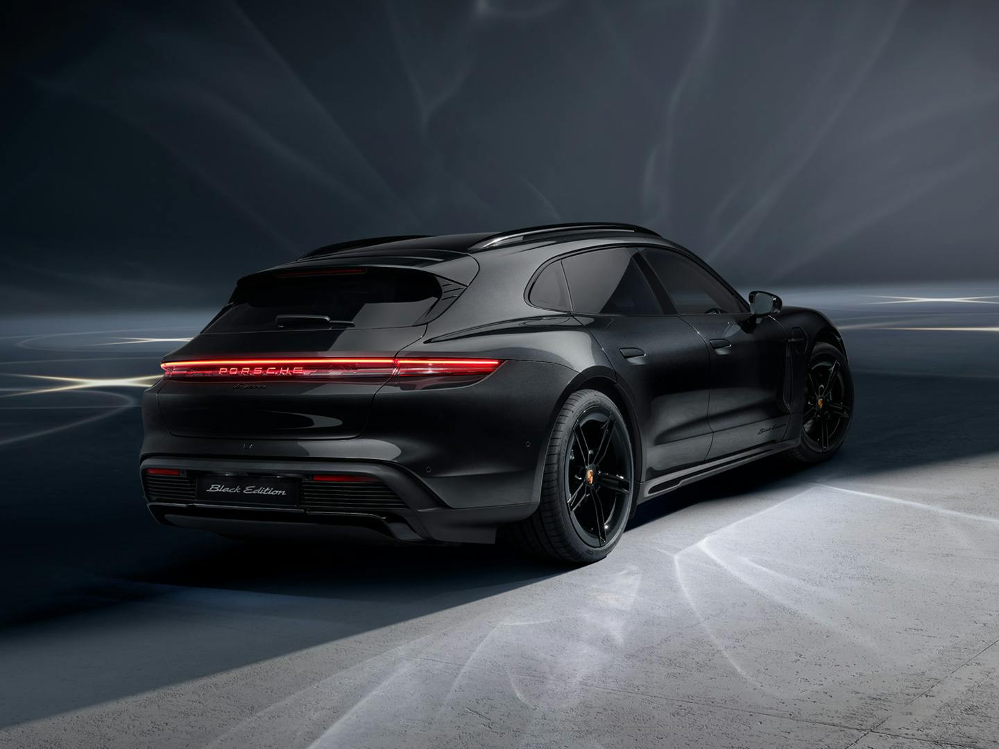 A rear view of the Taycan Sport Turismo Black Edition that is situated in a studio environment.