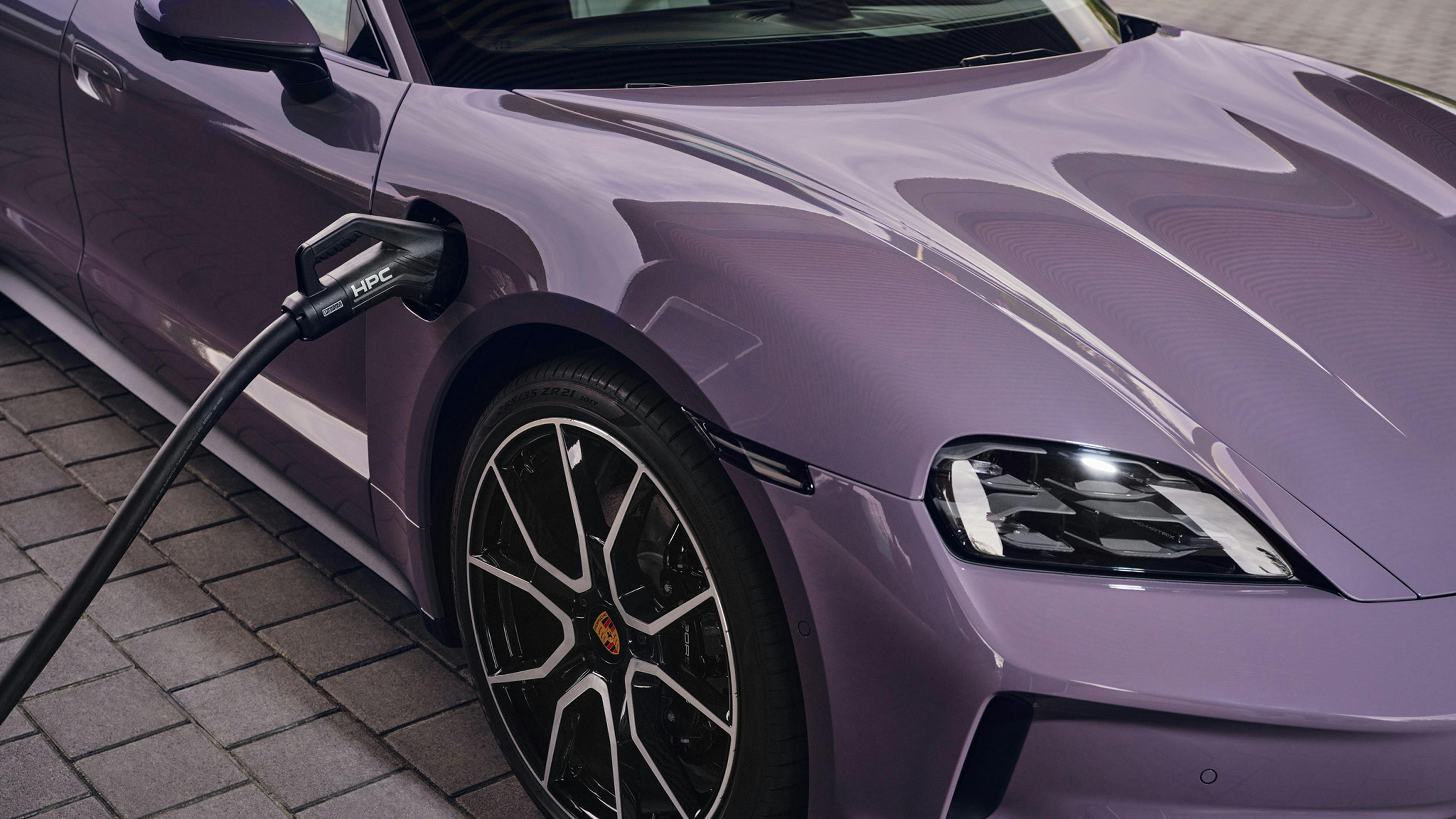 View of the charging socket on the front of the Porsche Taycan Sport Turismo. A charging cable is plugged into it.