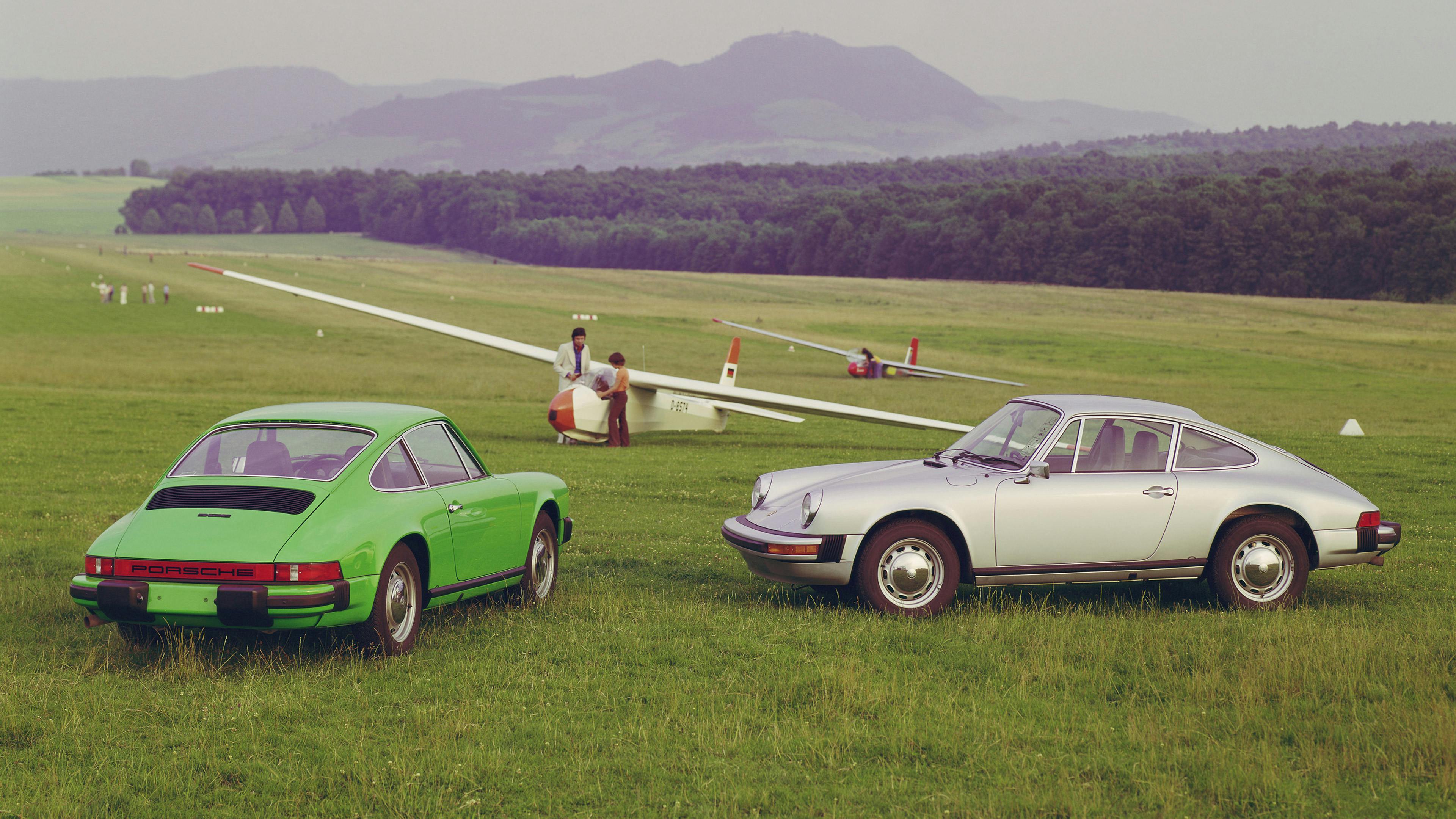 Two Porsche 912 E 2.0s (1976), Green and Silver, parked on a meadow with gliders.