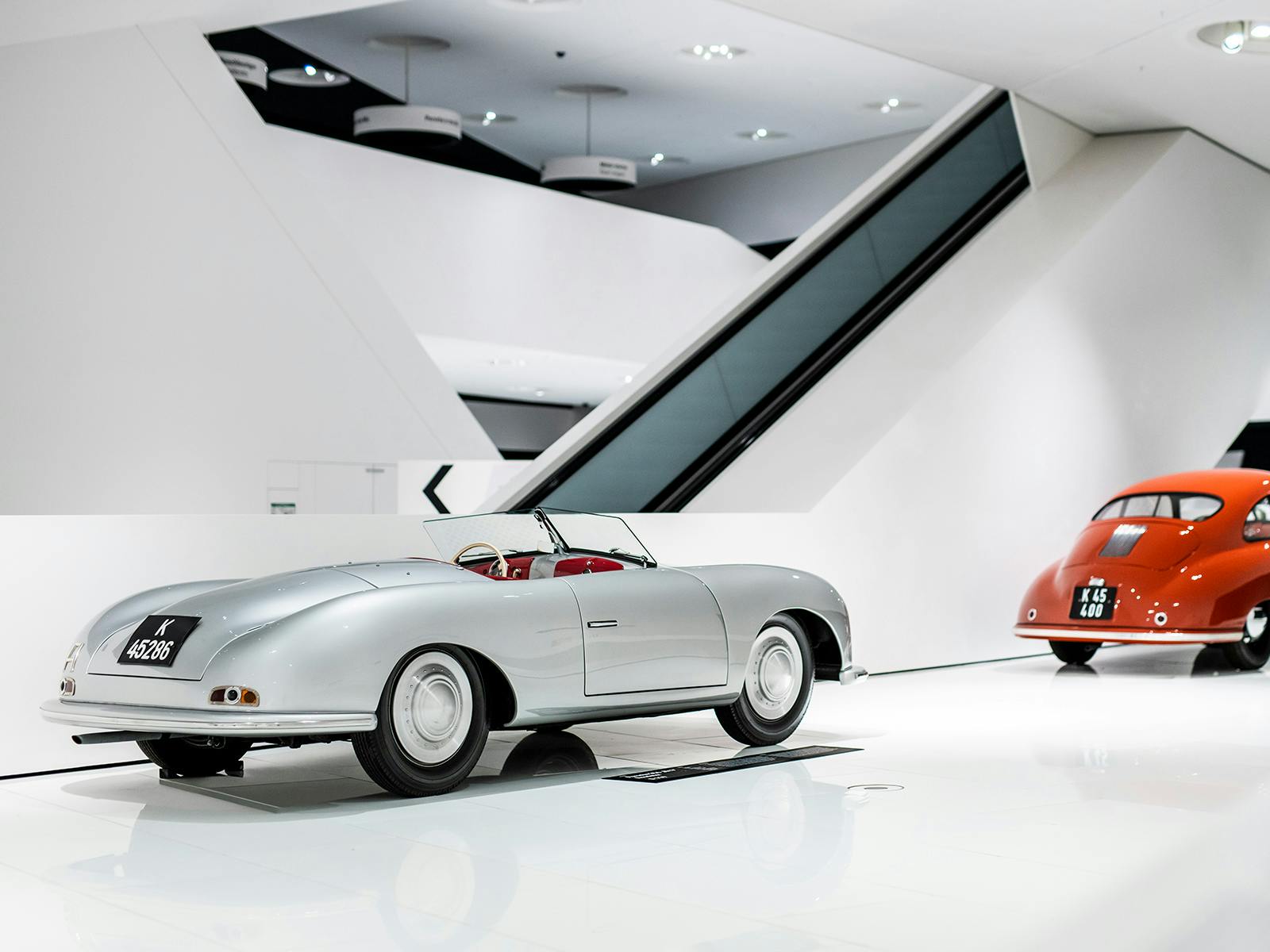 Weitläufiger weißer Raum mit einem Oldtimer Porsche im Hintergrund