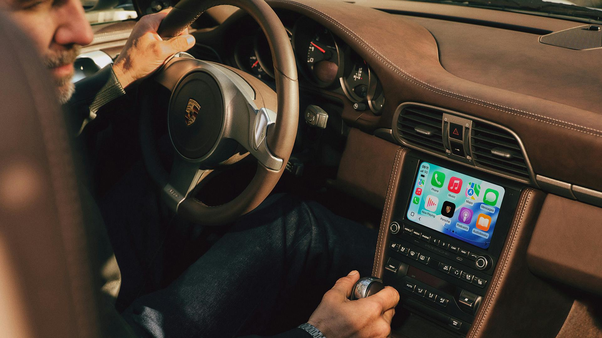 A man is driving a Porsche 911 (Type 997) fitted with Porsche Classic Communication Management Plus.