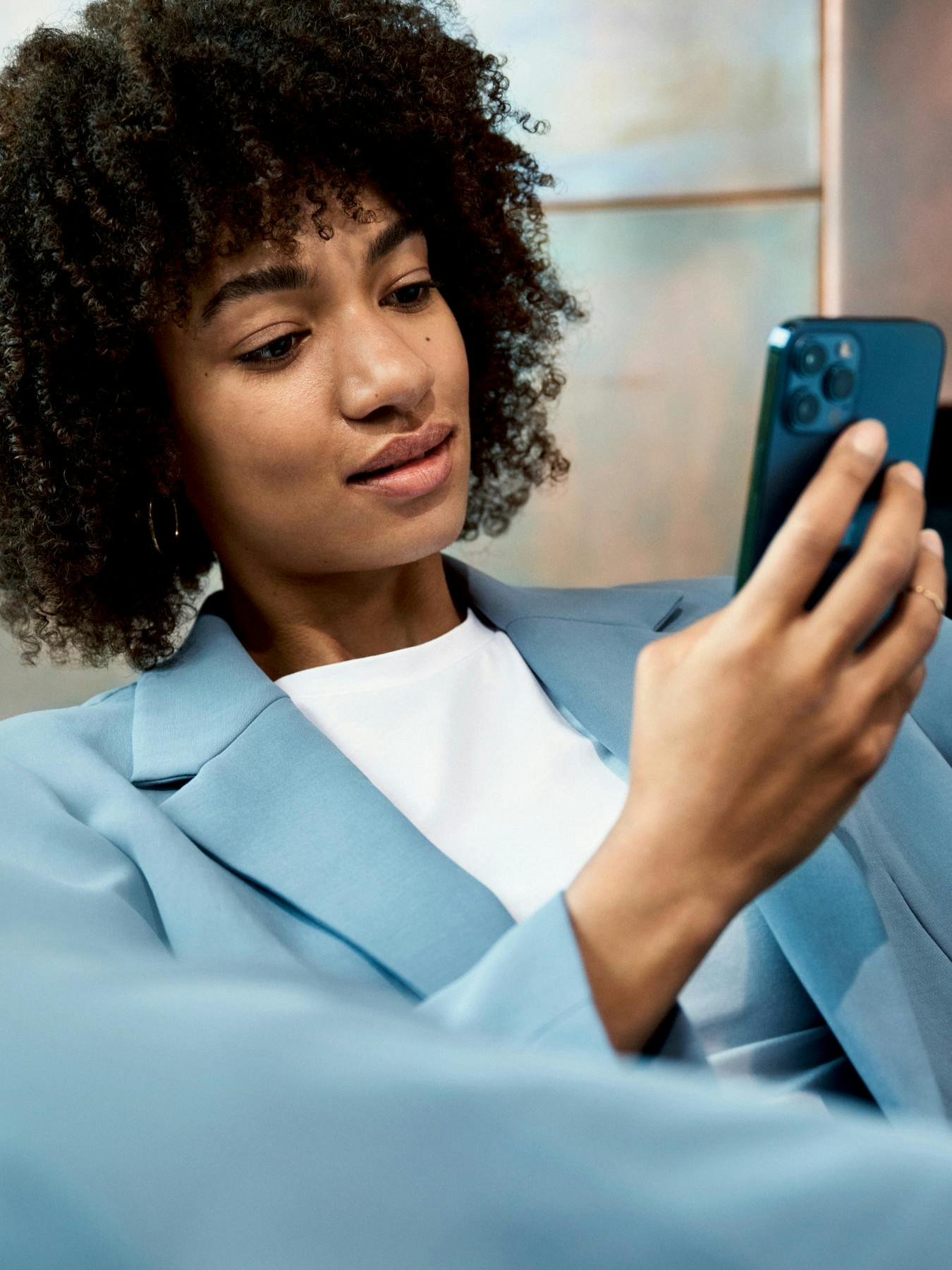 A woman in a blue suit looking at her smartphone.