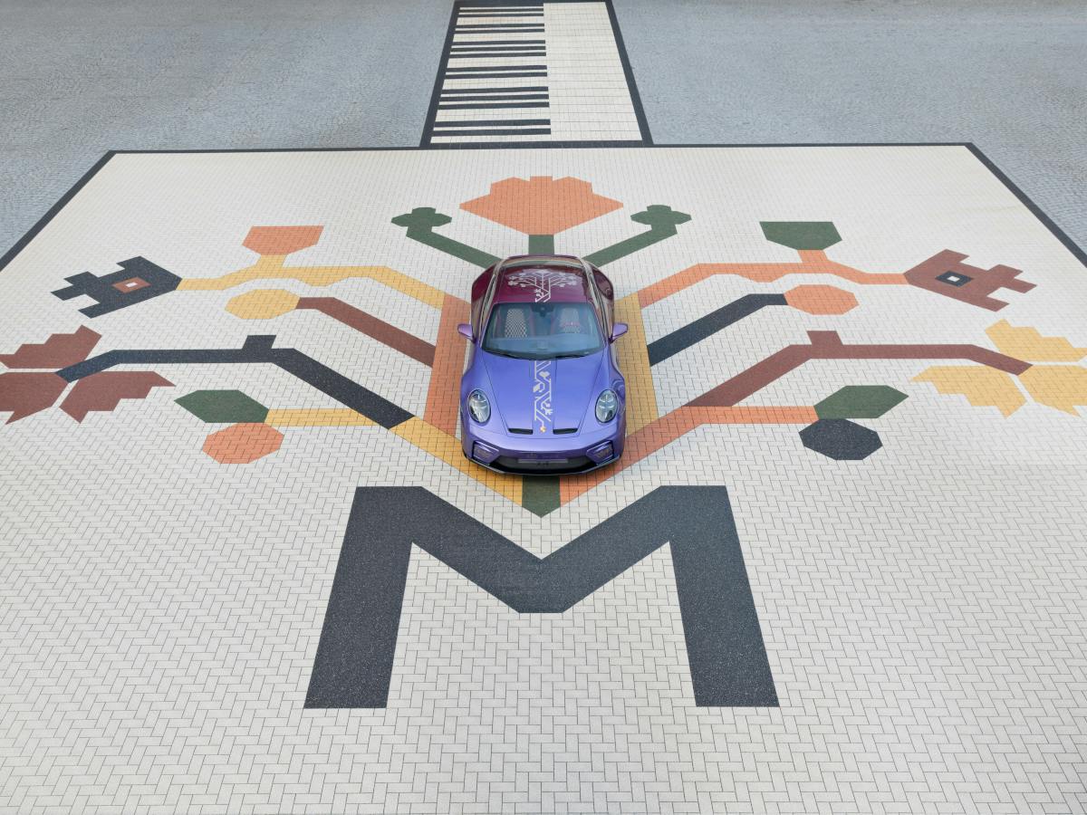 Top view of a Porsche 911 GT3 (992 II) with Touring Package positioned on a decorative mosaic featuring a stylized tree motif and geometric patterns on a cobblestone-like surface.​