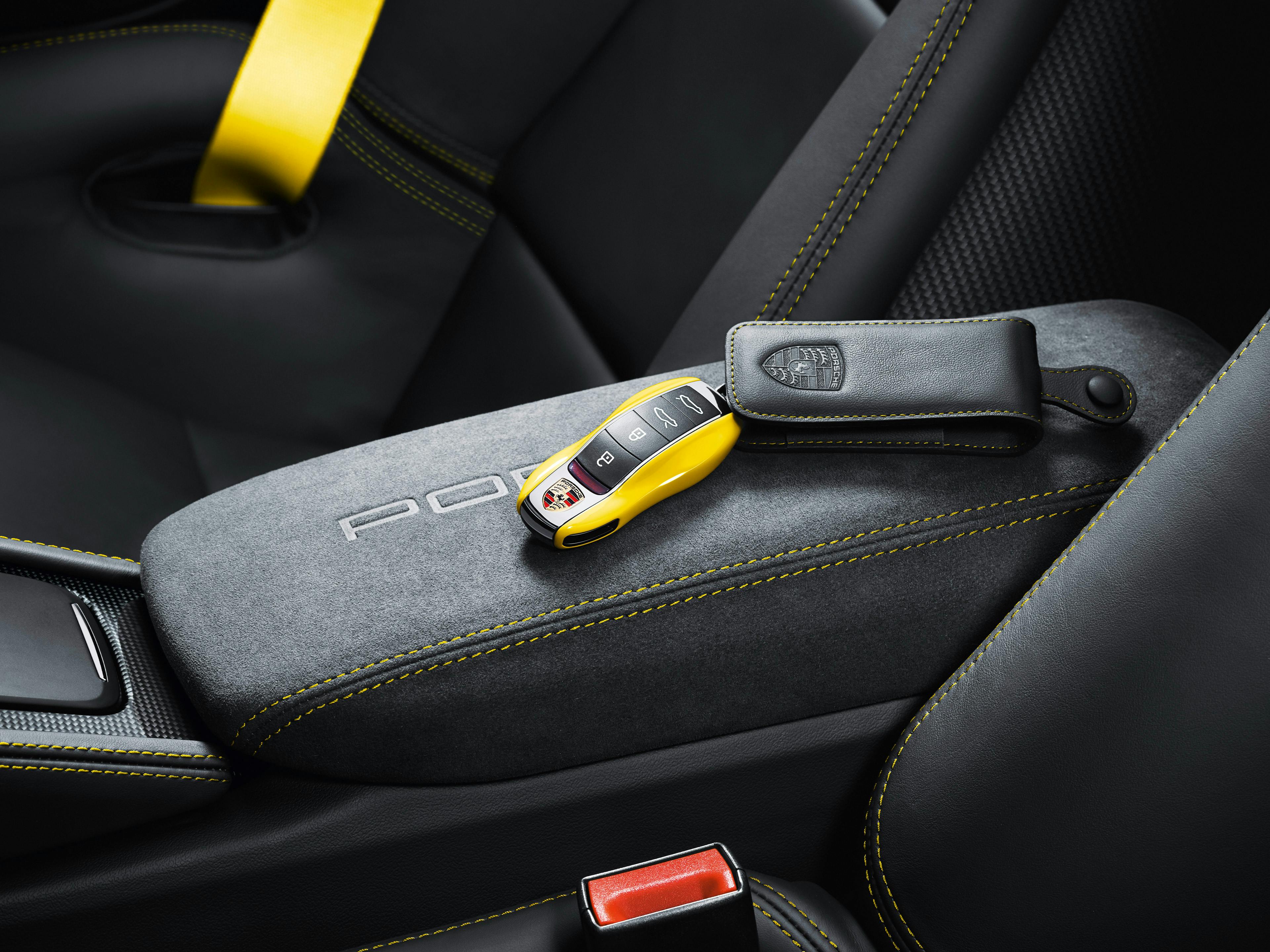 Une clé de véhicule Porsche laquée jaune se trouve sur la console centrale.