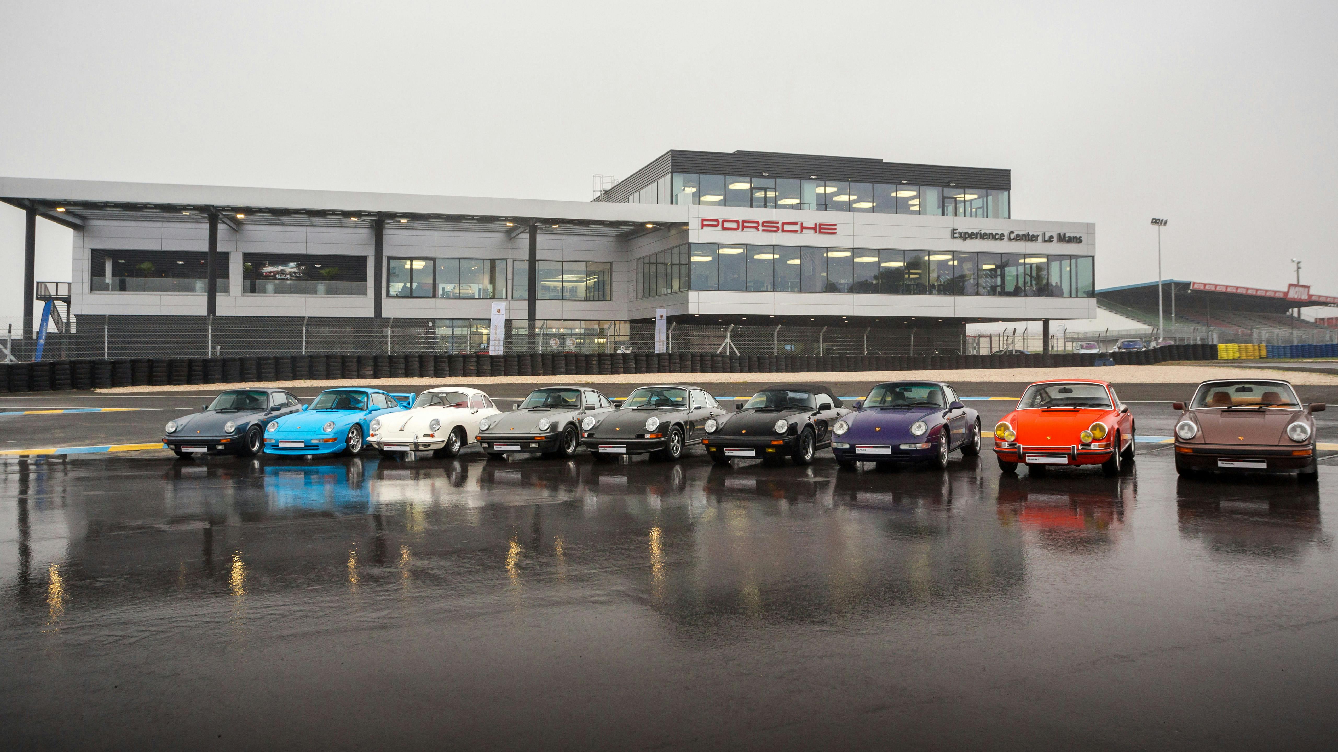 Les neuf voitures restaurées sont placées côte à côte devant le Porsche Experience Center Le Mans.