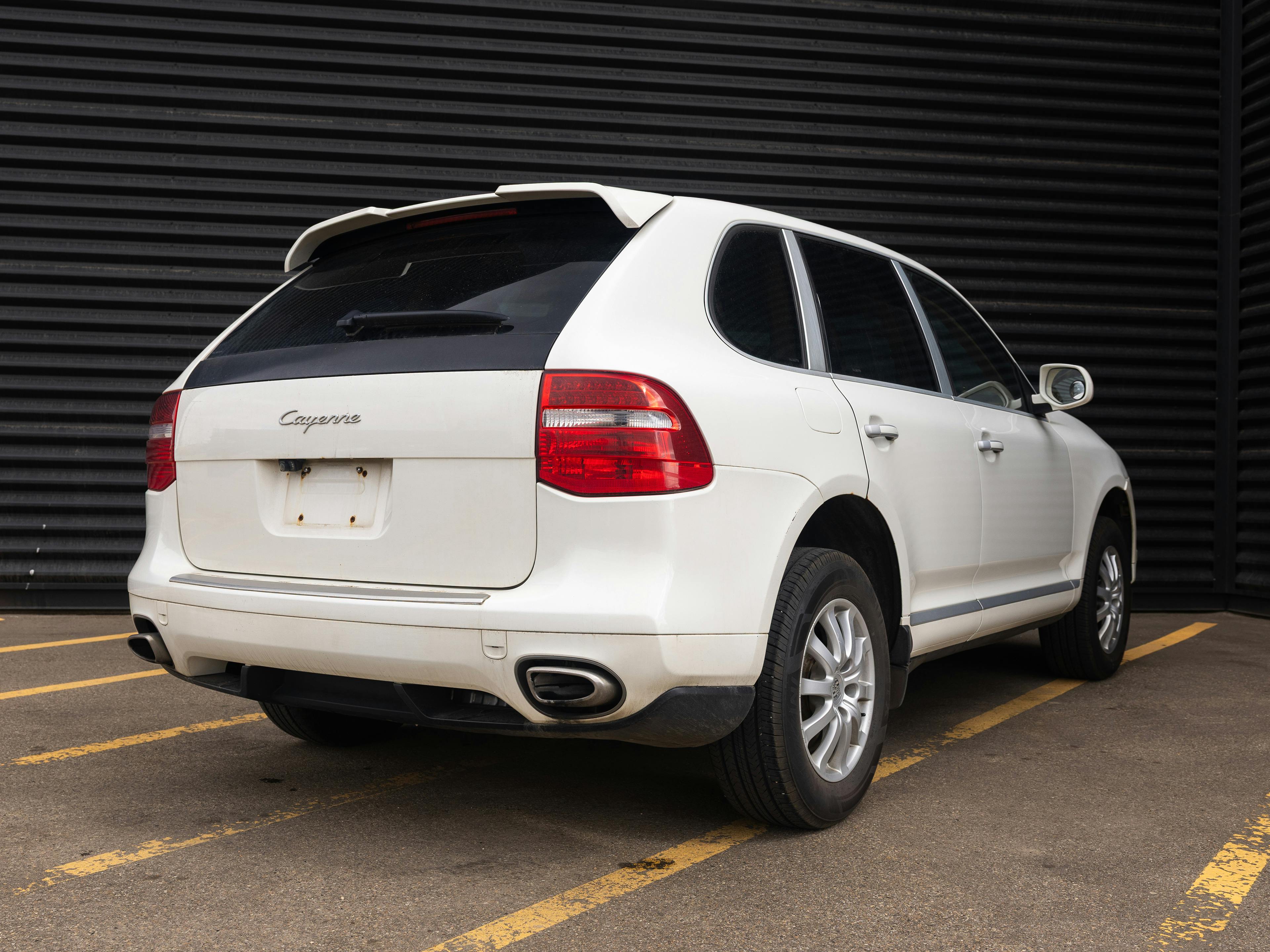 Edmonton – A white Porsche Cayenne parked in a parking lot with a black wall in the background.