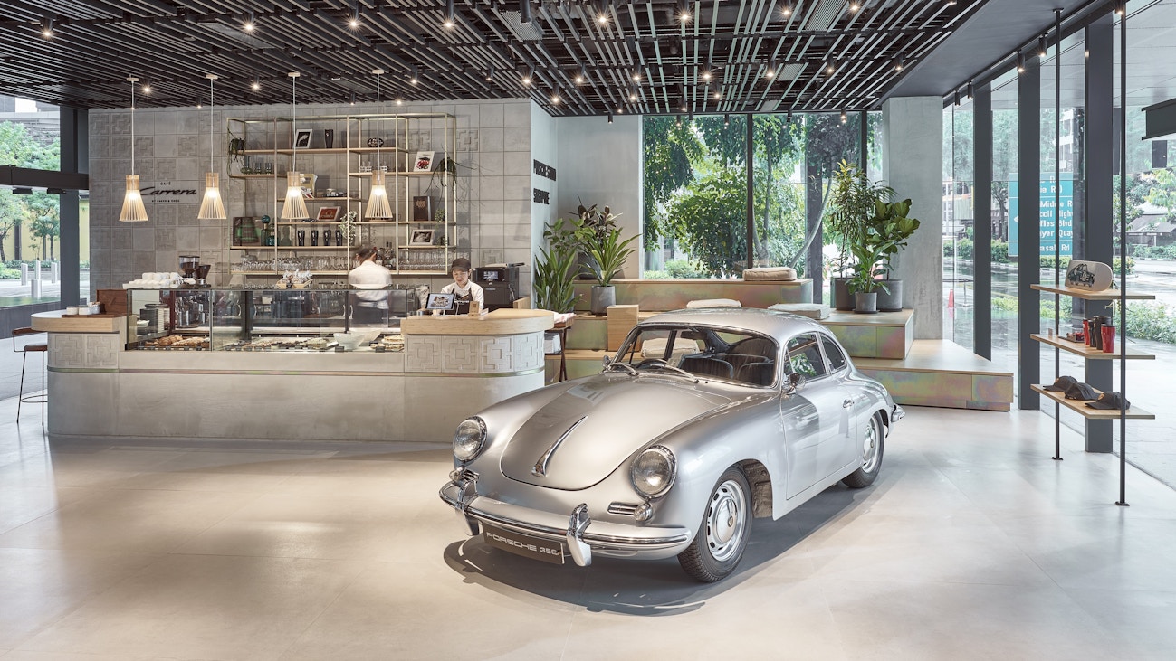 Image 11: General view of Porsche Studio Singapore, with a silver Porsche 356 Coupe parked next to Café Carrera by Baker & Cook.
