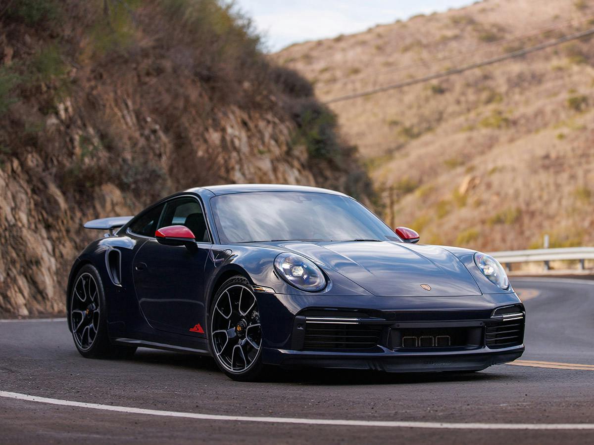 A 911 Turbo S coloured in Xblue driving on a coastal road.