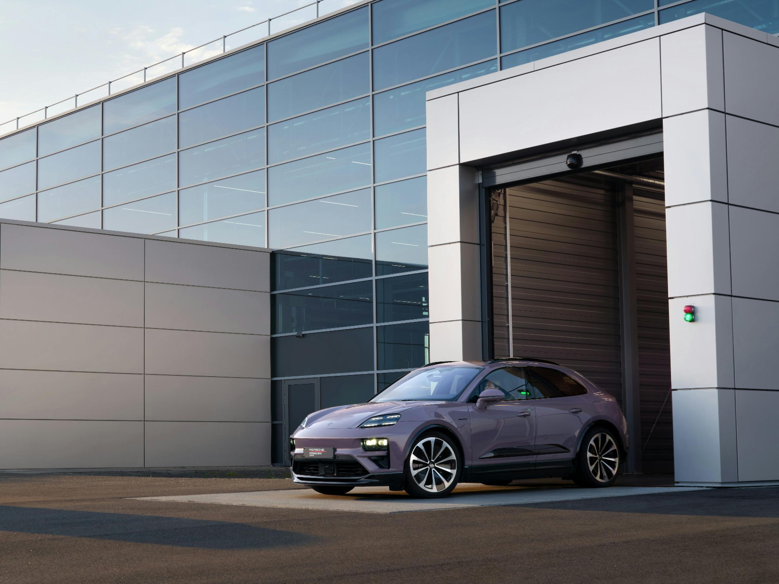Porsche Macan 4 in Provence paint finish parked in front of the garage of a Porsche dealership.