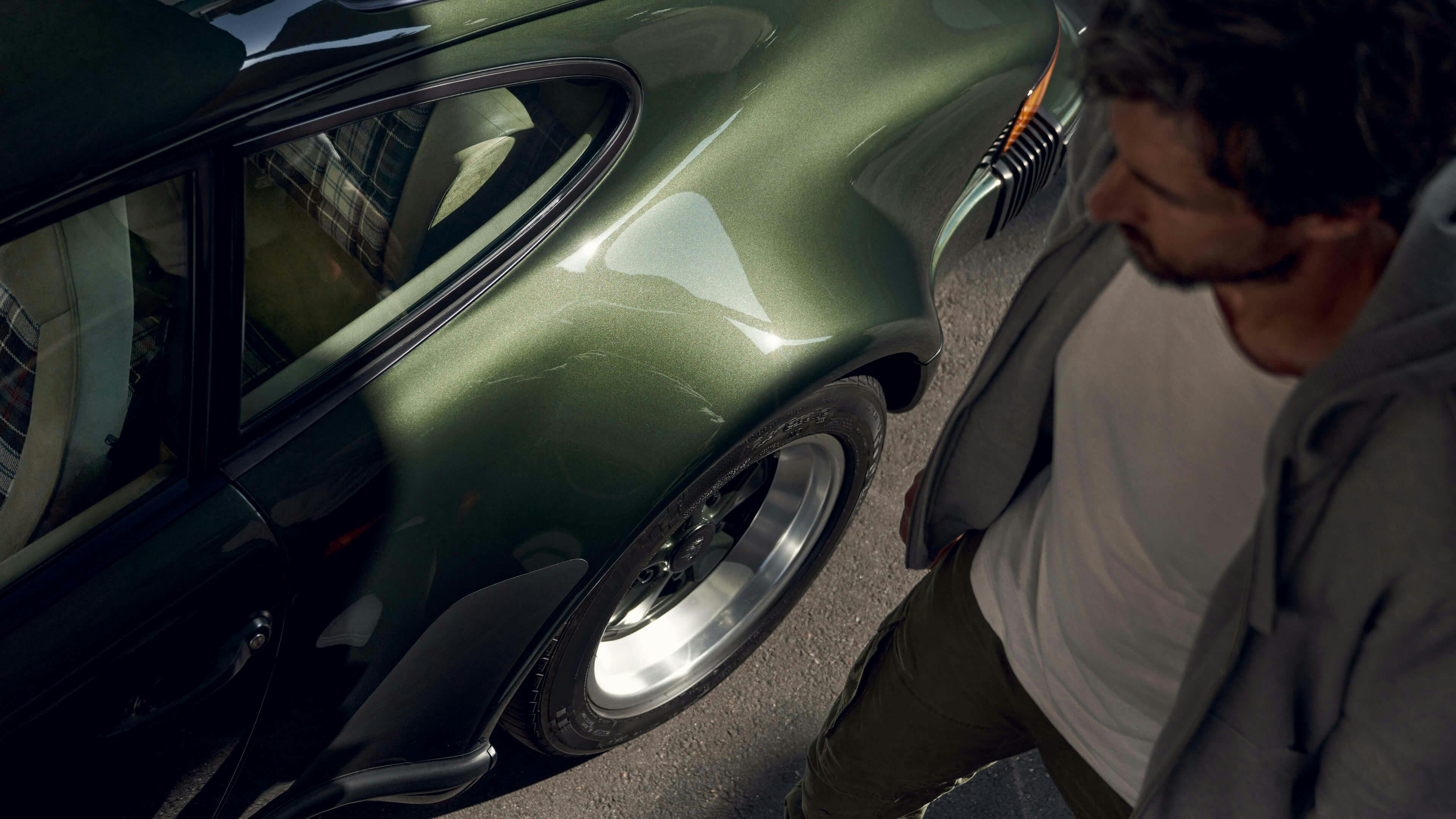 Man standing next to a dark green Porsche 911 G-model