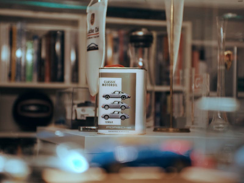 Pack shot of Porsche Classic Motoroils including machine cleaning cloth on a workbench in a garage.
