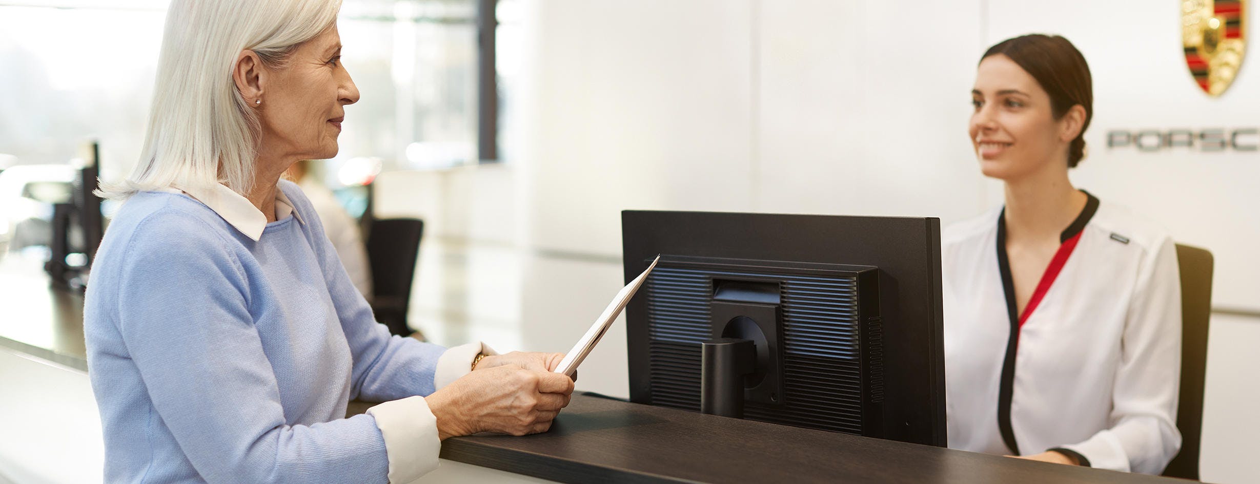 Elderly woman discussing warranty with office employee.