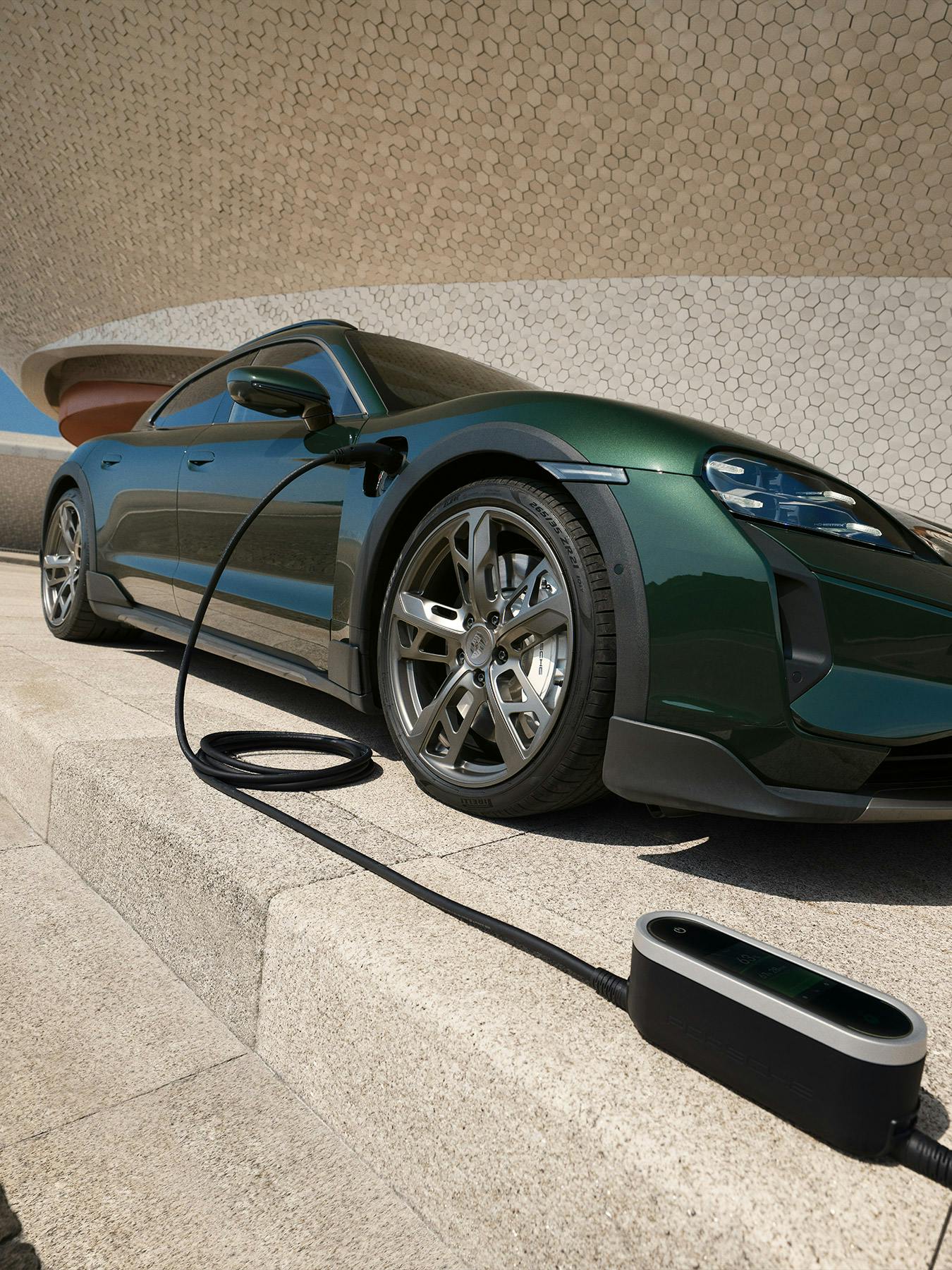 A Porsche Taycan Turbo Cross Turismo charging at a Wallbox in front of a modern villa.