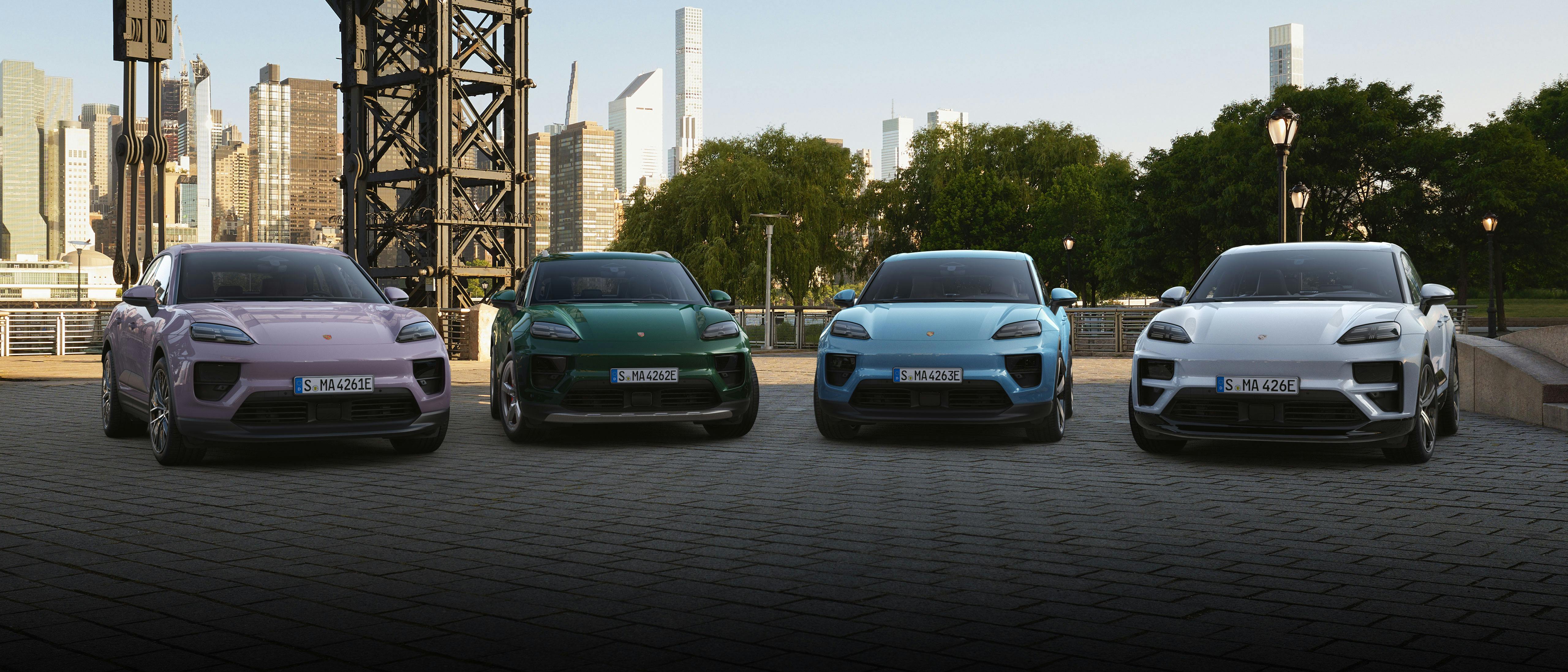 The Macan Electric, Macan 4, Macan 4S Electric and Macan Turbo Electric parked in an urban environment from a frontal view with skyscrapers in the background.