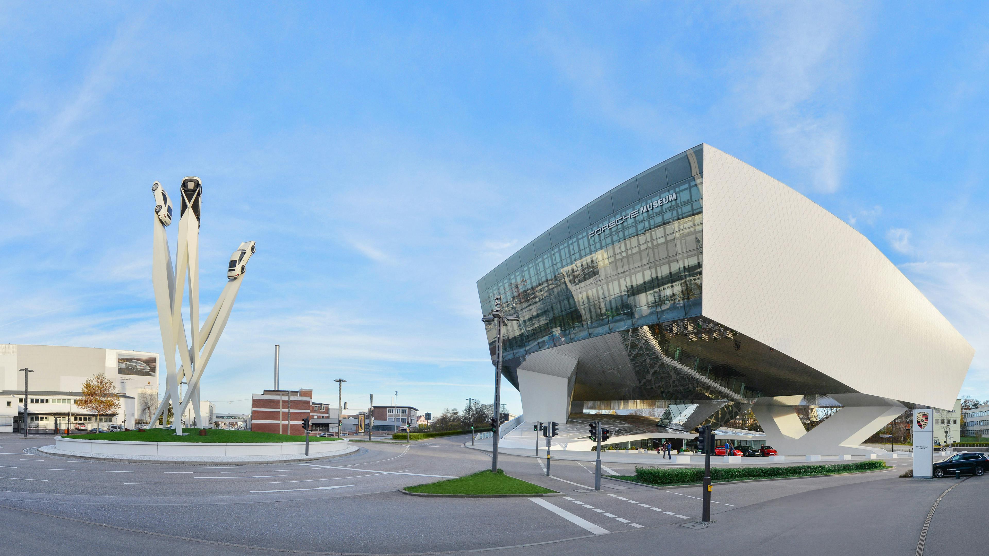 The exterior view of the Porsche Museum in Stuttgart with the Porsche sculpture in front of it.